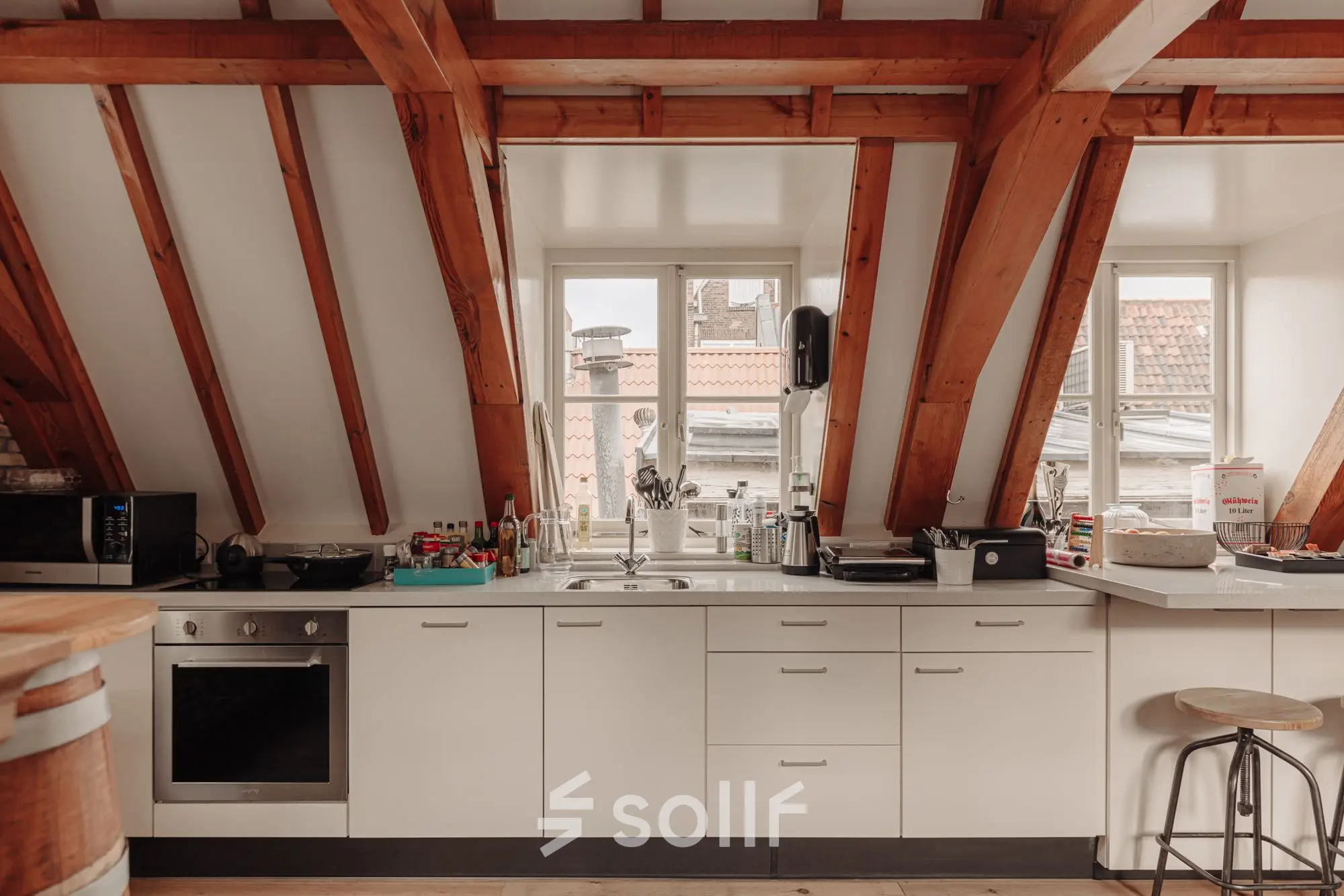 Bright kitchen area under exposed wooden beams with a modern counter setup at Prins Hendrikkade 14, ideal for breaks in an office space rental.