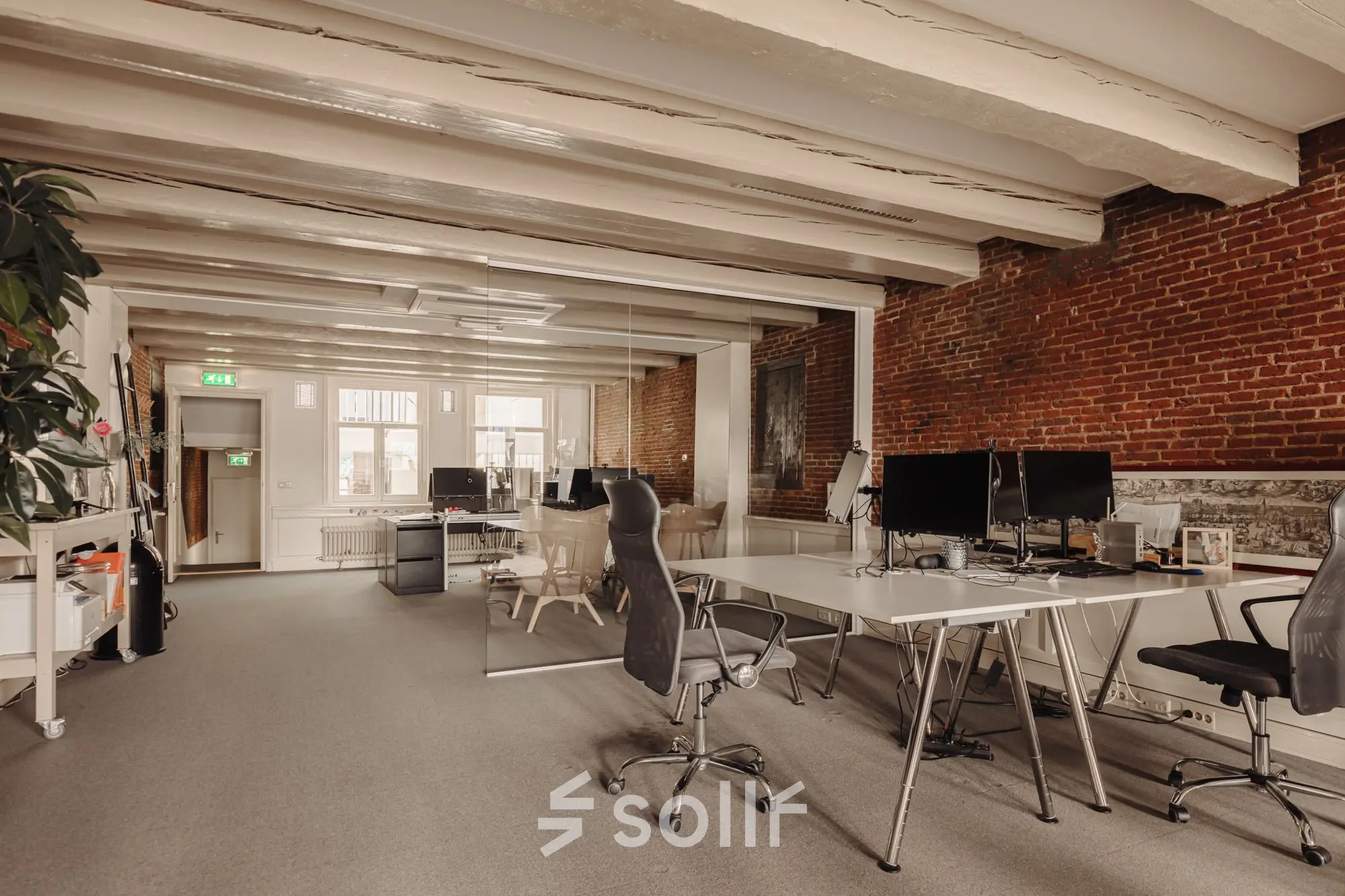 Spacious office interior at Prins Hendrikkade 14, in Amsterdam Center with desks, chairs, and exposed brick walls, perfect for office space rental.