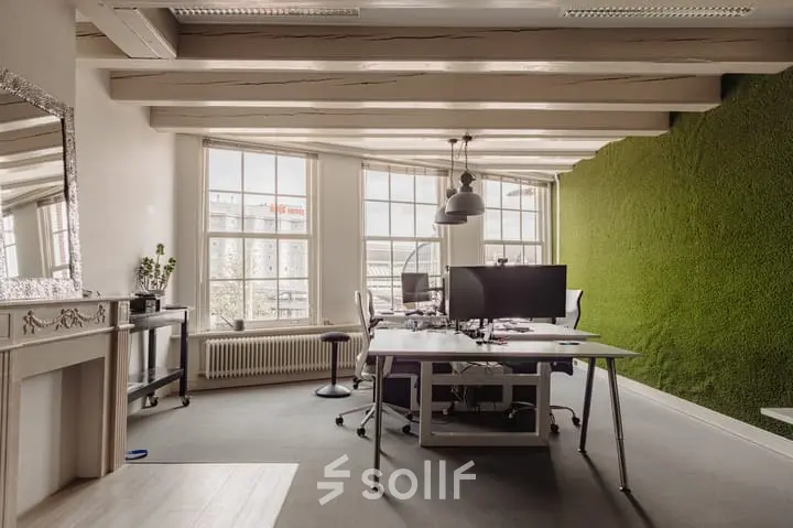 Bright office space with large windows, furnished with desks, chairs, and computers at Prins Hendrikkade 14, Amsterdam Center, perfect for office space rental.