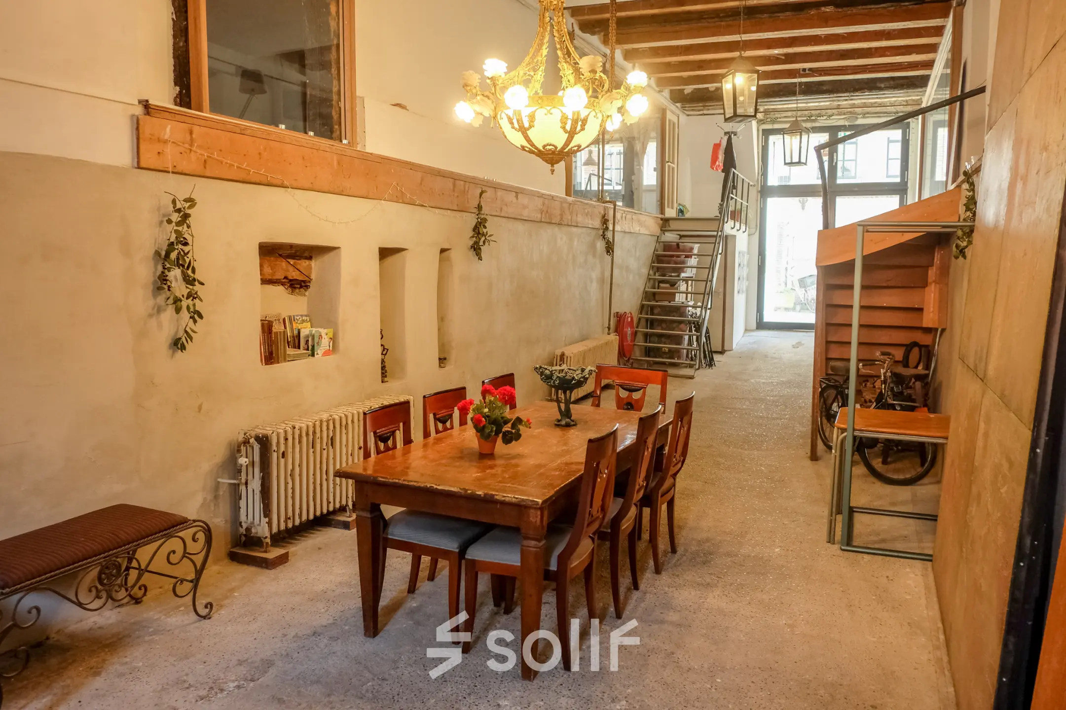 Charming office space with wooden beams and a chandelier at Prinseneiland 23A, Amsterdam Center, ideal for office space rental. Features a long table with chairs perfect for meetings.