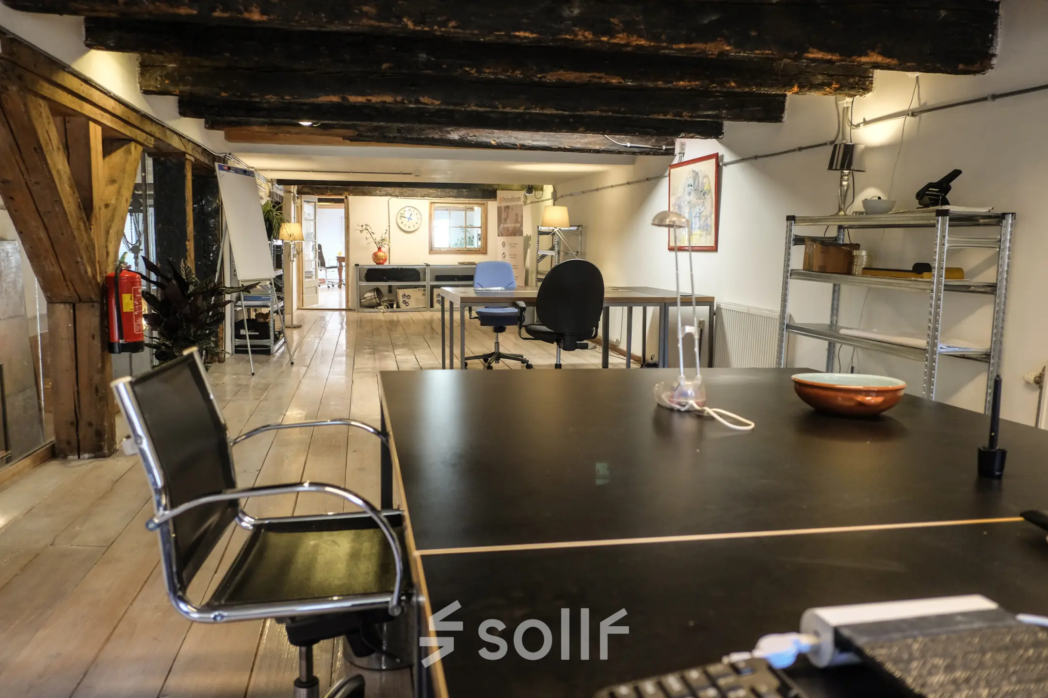 Rustic office space with wooden beams, modern desks, and chairs available for rent on Prinseneiland 23A, Amsterdam Center.