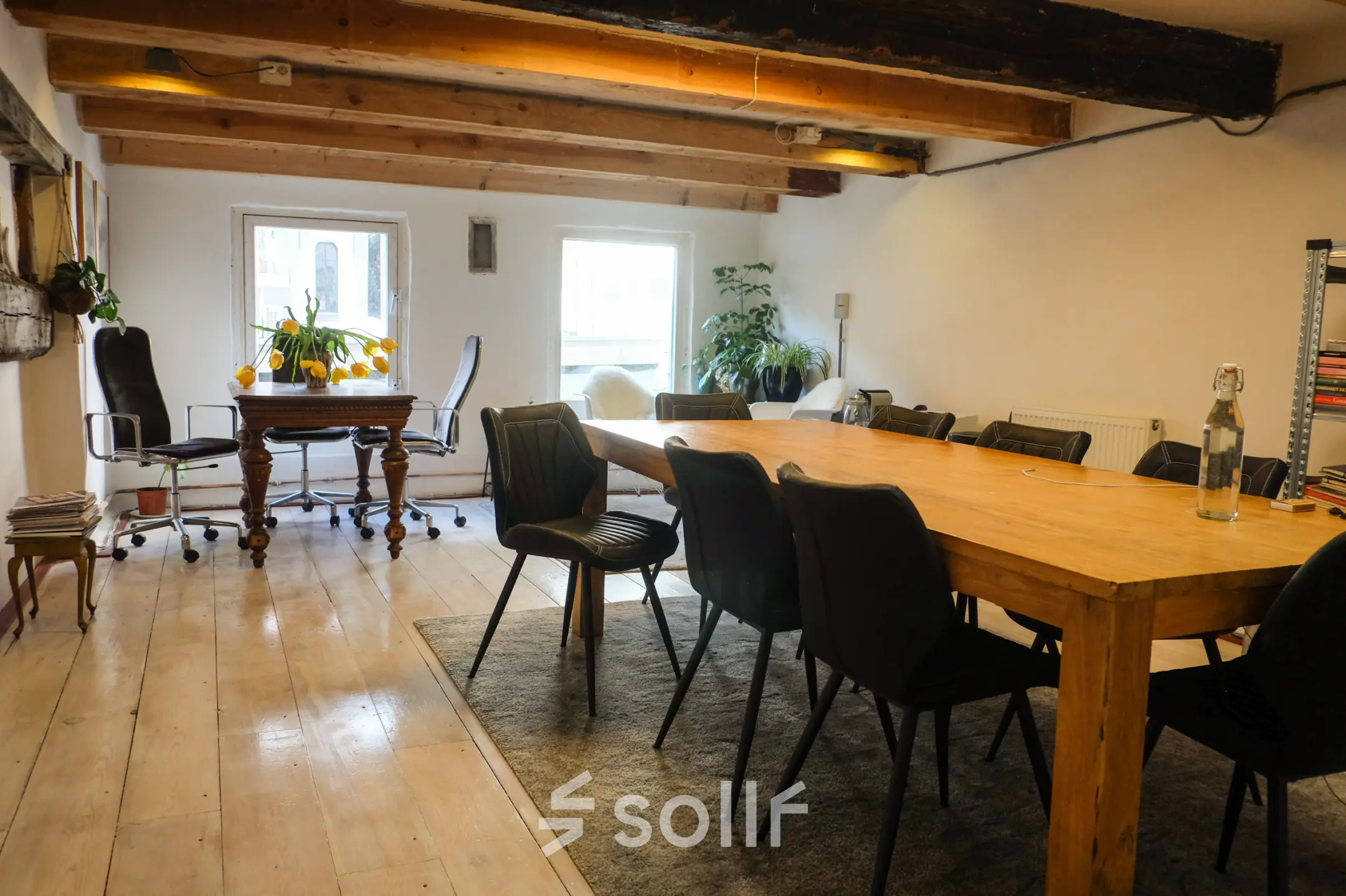 Spacious office with wooden beams and a long table, perfect for meetings, located in Amsterdam Center. Ideal office space rental with natural light.