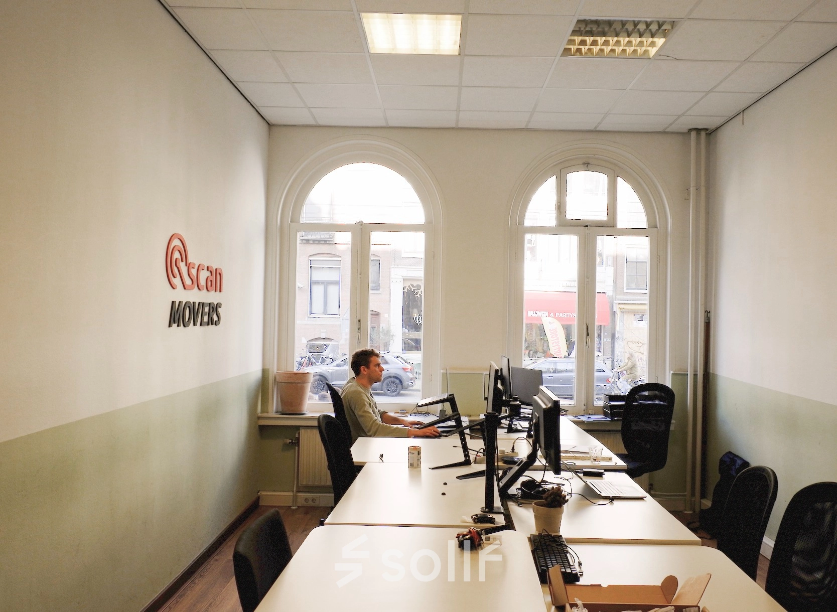 Office space at Raadhuisstraat 15, Amsterdam Center, featuring a furnished workspace with a person working at a desk, suitable for rent office space or office to rent needs.