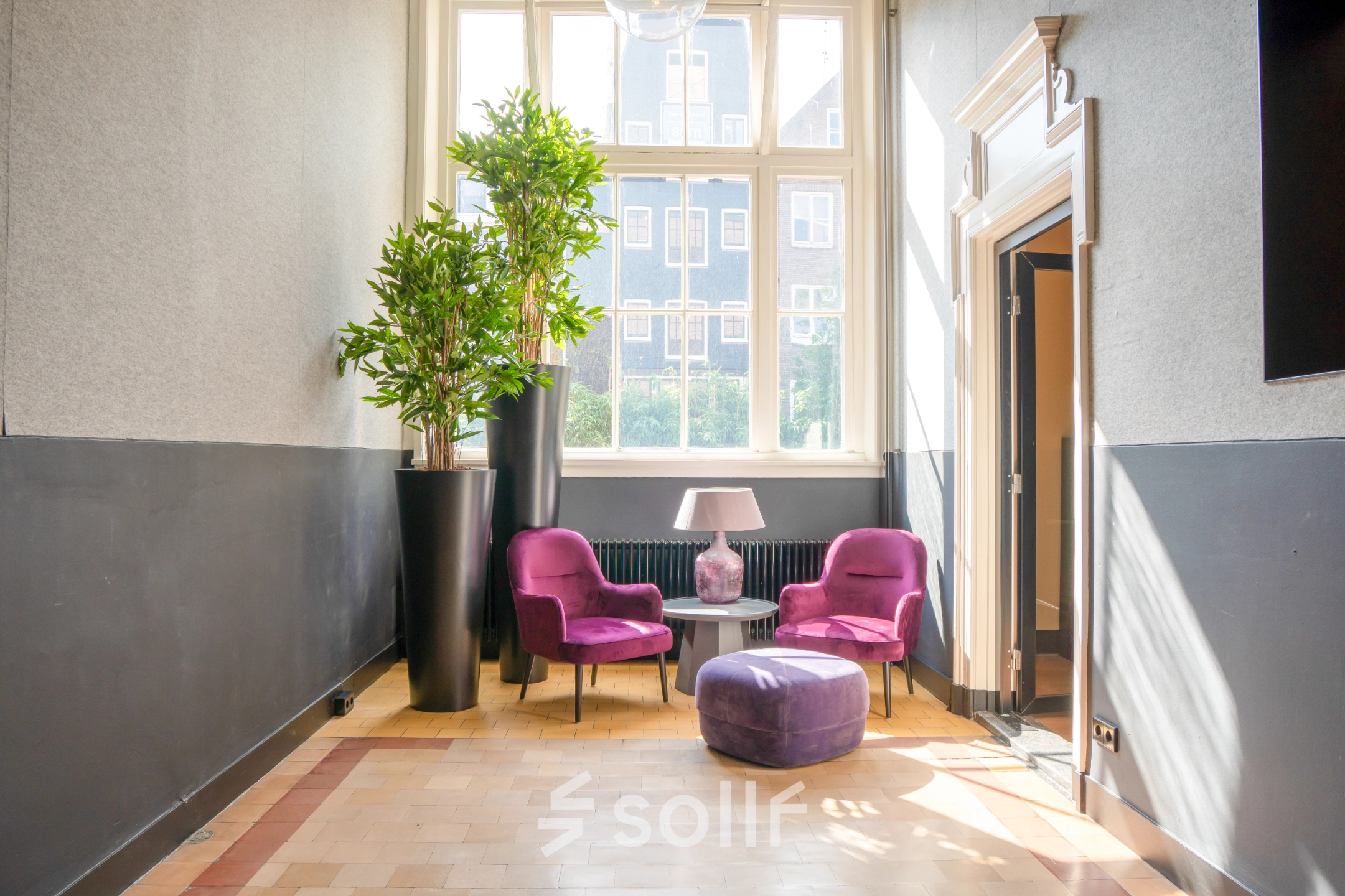 Bright office lounge at Raamplein 1, Amsterdam Center with vibrant purple chairs and a window view, perfect for office space rental.