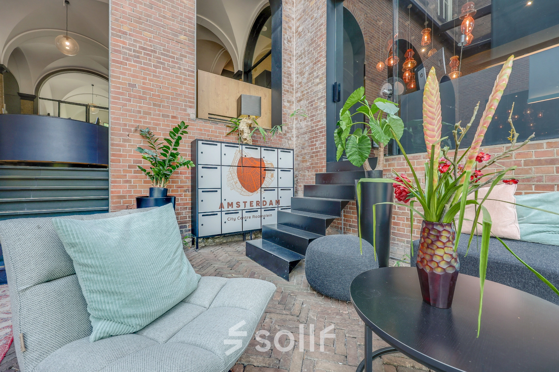 Inviting office space for rent in Amsterdam Center at Raamplein 1, featuring stylish furnishings with comfortable seating and decorative plants.