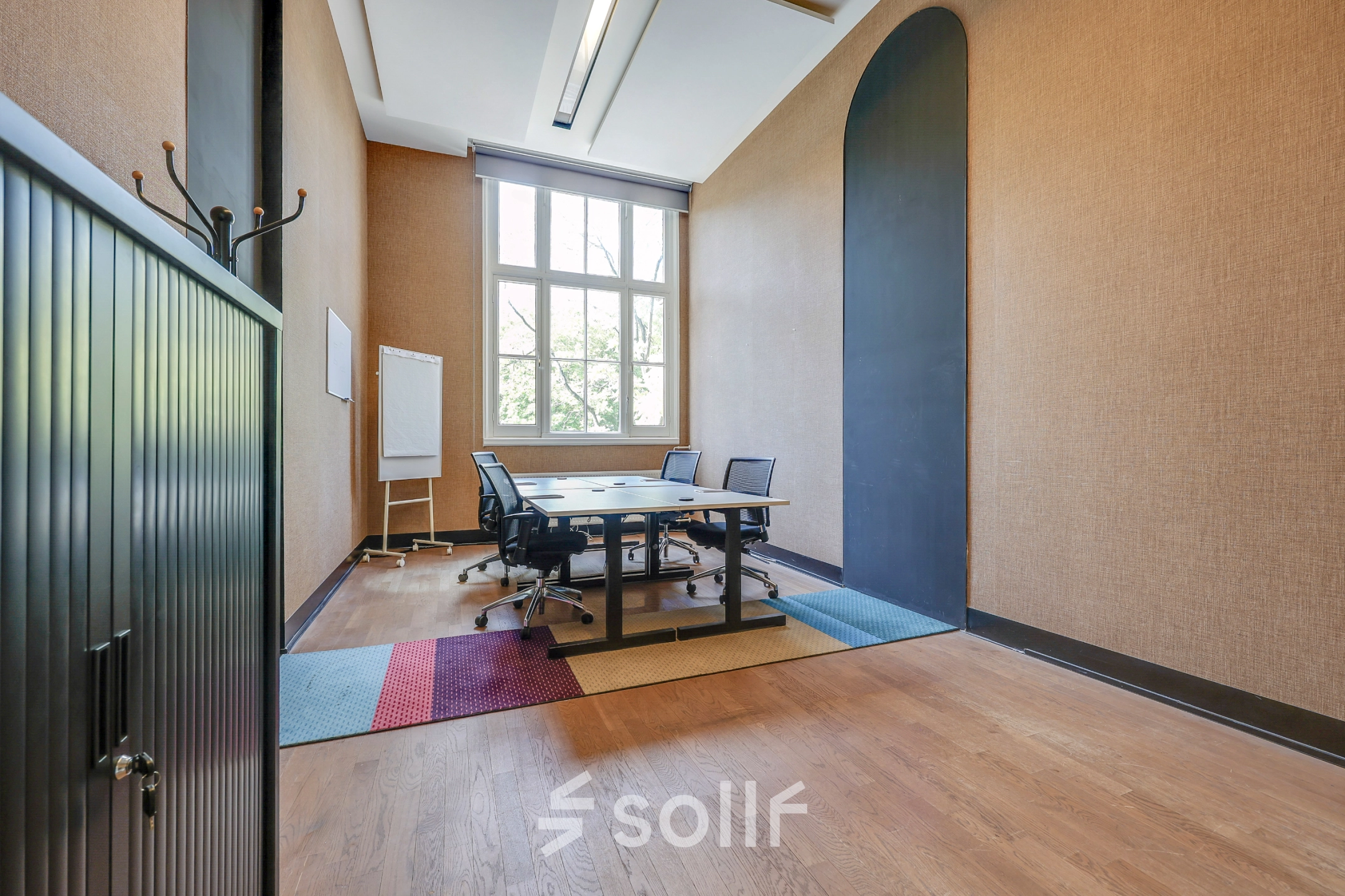 Interior view of a furnished office to rent at Raamplein 1, Amsterdam Center, featuring a meeting table with chairs and a large window.