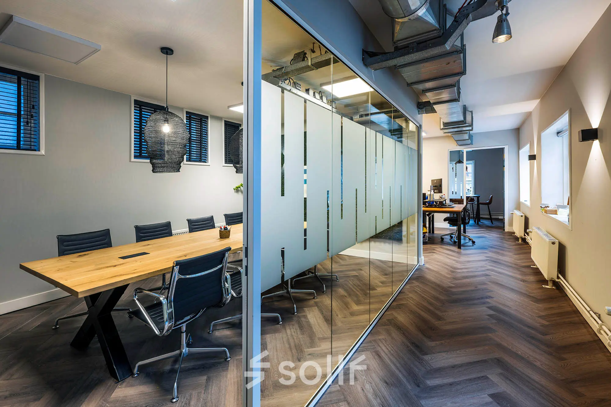 Contemporary office space in Amsterdam Center featuring a glass-walled conference room and modern furnishings, perfect for office space rental at Rapenburgerstraat 173.