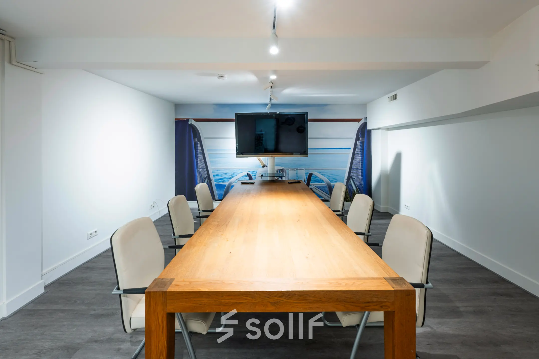 Interior view of a furnished office space for rent at Rokin 105, Amsterdam Center, featuring a wooden conference table surrounded by chairs and a wall-mounted screen.
