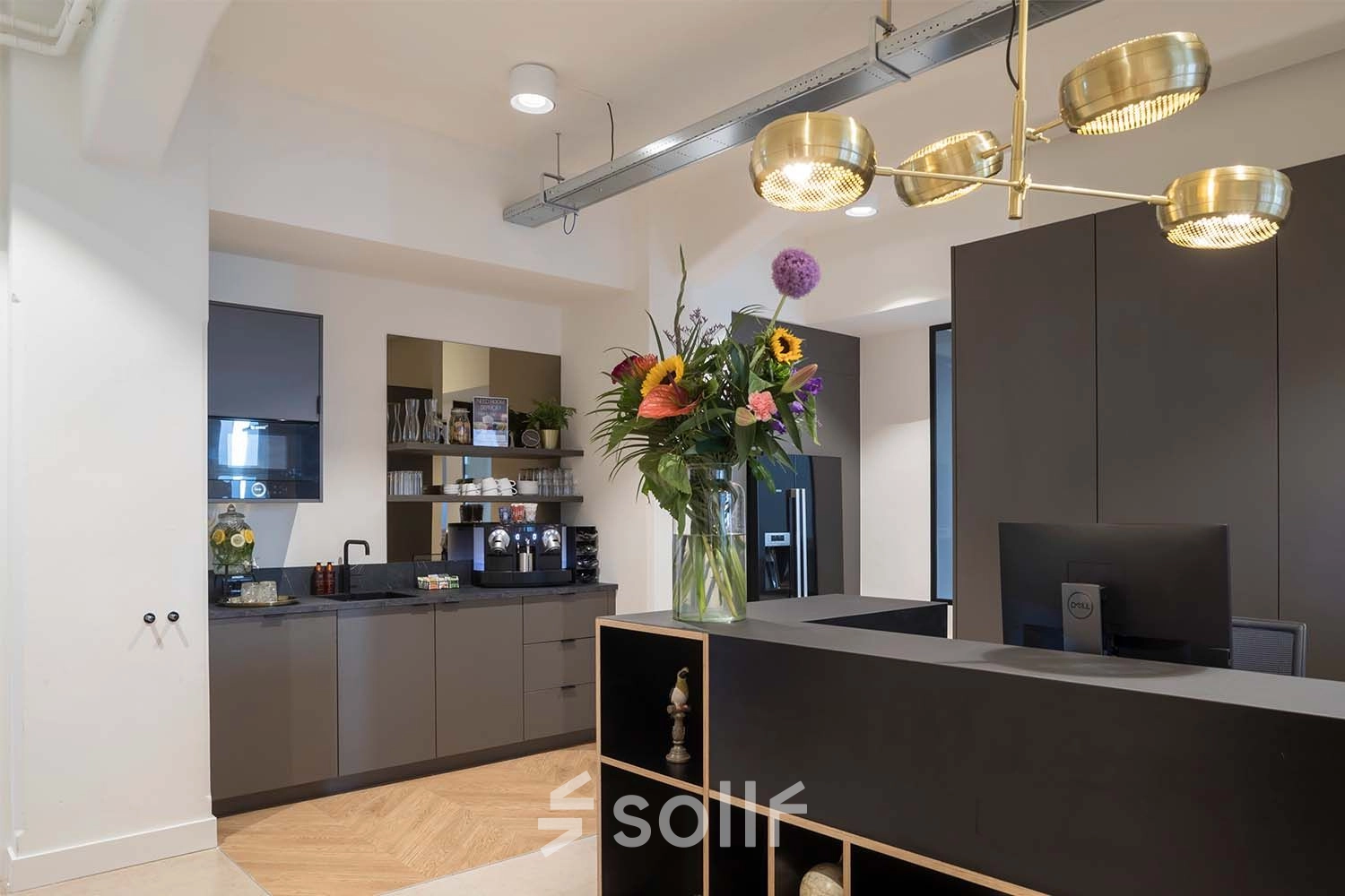Modern office space in Amsterdam Center with a reception area featuring a stylish desk, decorative lighting, and vibrant floral arrangement.