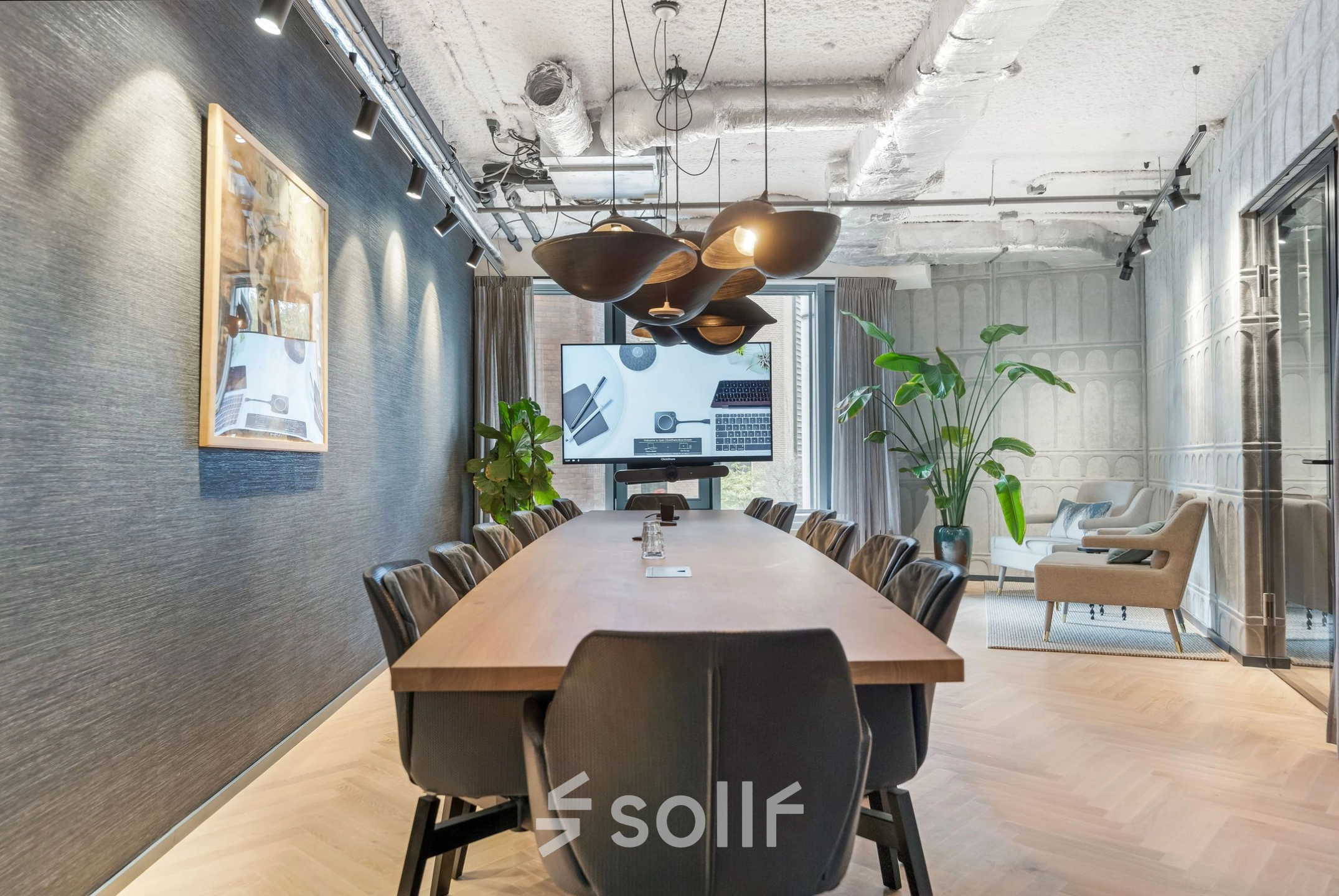 Conference room at Stadhouderskade 55, Amsterdam Center, featuring modern furnishings and ample lighting. Ideal office space rental for meetings. Sleek design with a long table and chairs, accented by plants.