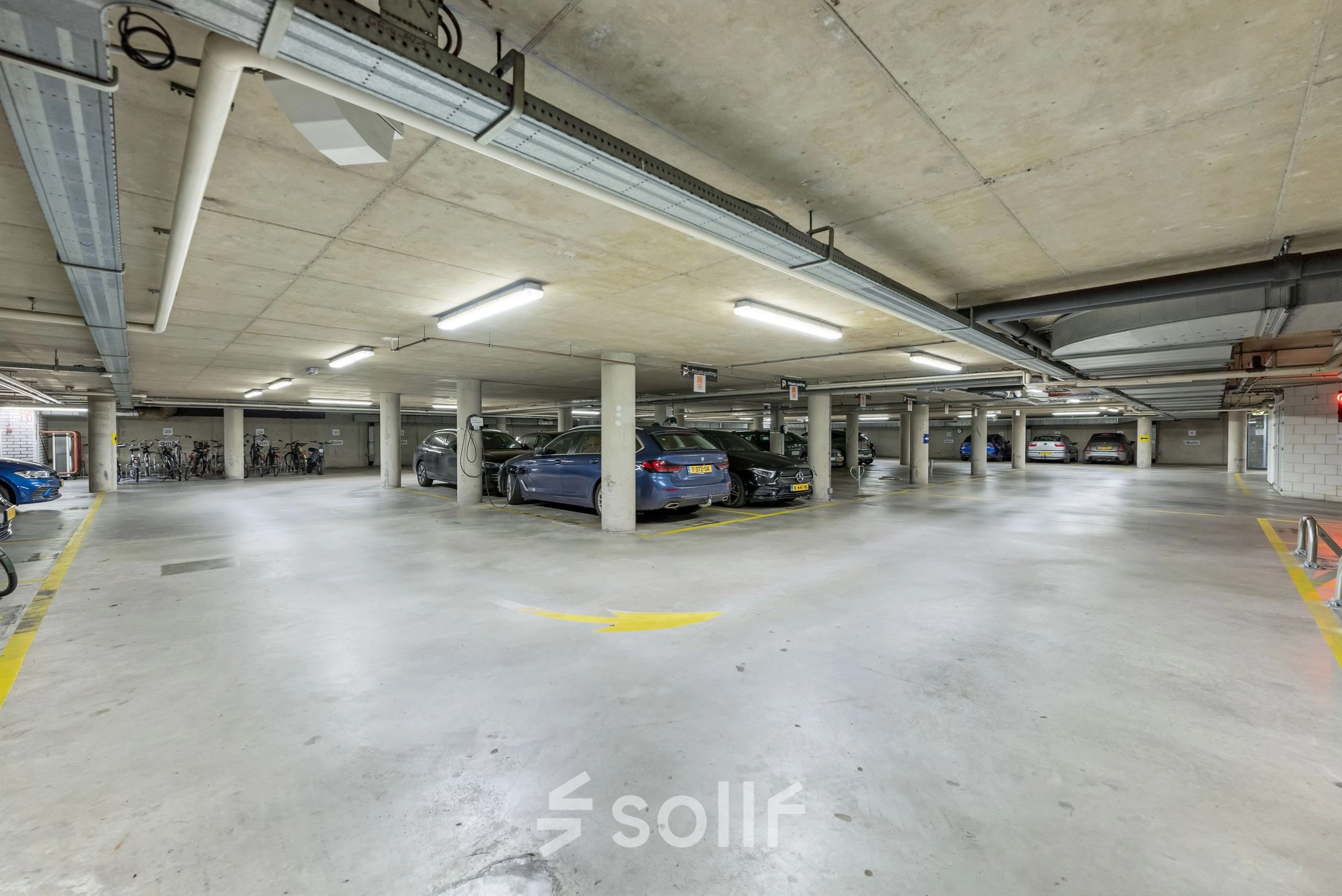 Spacious parking area with concrete ceiling and several parked cars, located at Stadhouderskade 55 in Amsterdam Center.