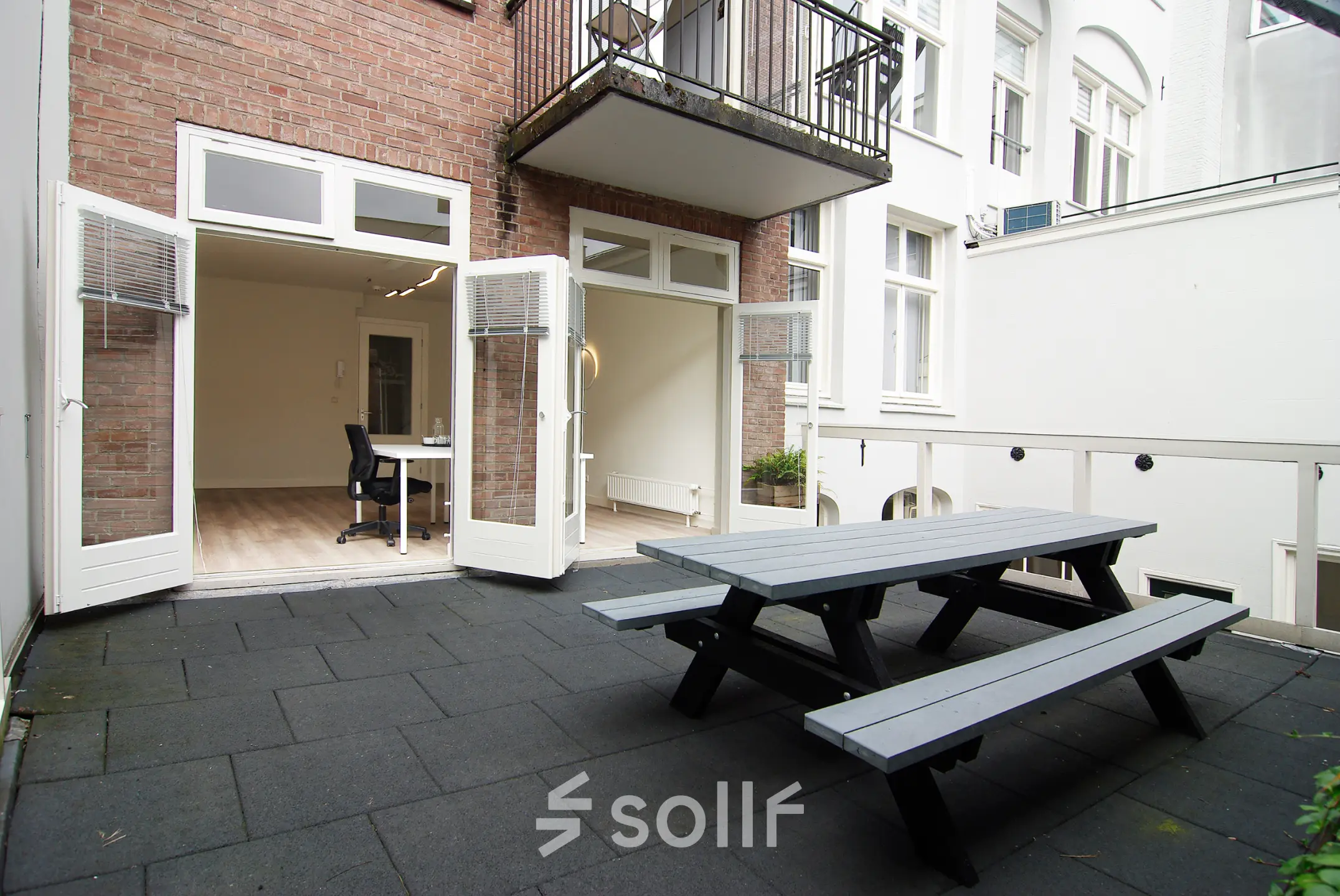 A furnished office space to rent at Warmoesstraat 149-151, Amsterdam Center, featuring an open patio with seating and a modern interior.