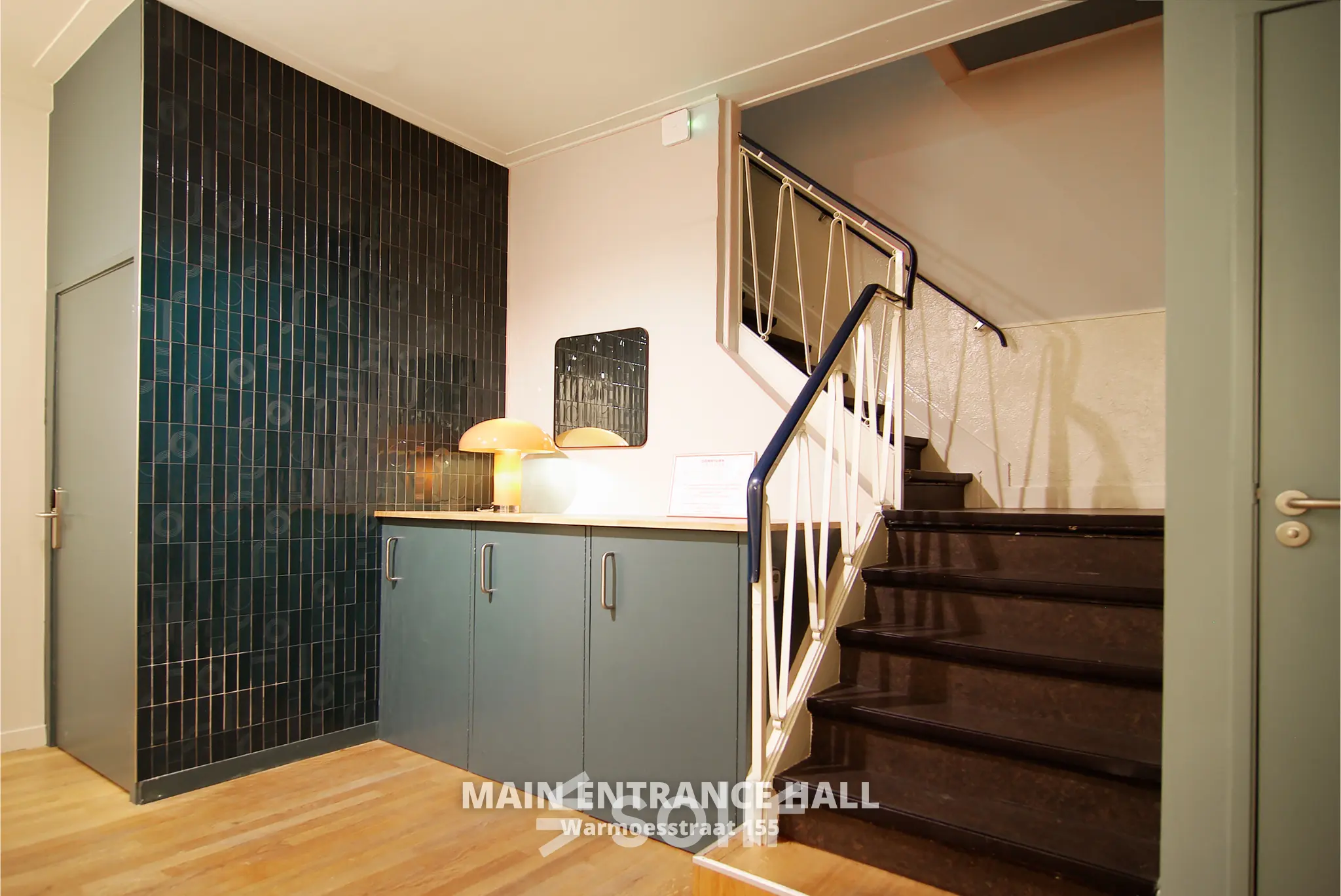 Main entrance hall of Warmoesstraat 155, featuring a staircase and cabinets, ideal for office space rental in Amsterdam Center.