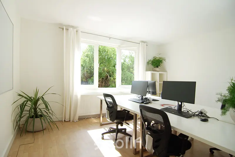 A well-lit office space rental on Warmoesstraat 155 in Amsterdam Center, featuring desks with computers and greenery. Ideal office to rent for focused work.