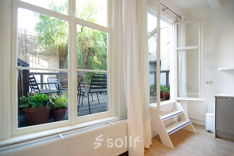 Bright office space with large windows overlooking a terrace at Warmoesstraat 155, Amsterdam Center, available for rent. Perfect for those seeking a serene and inspiring environment.