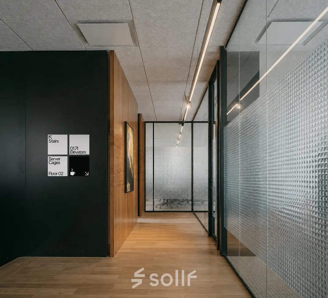 Modern office hallway with glass walls and wooden flooring at Weteringschans 26, Amsterdam Center, ideal for office space rental.