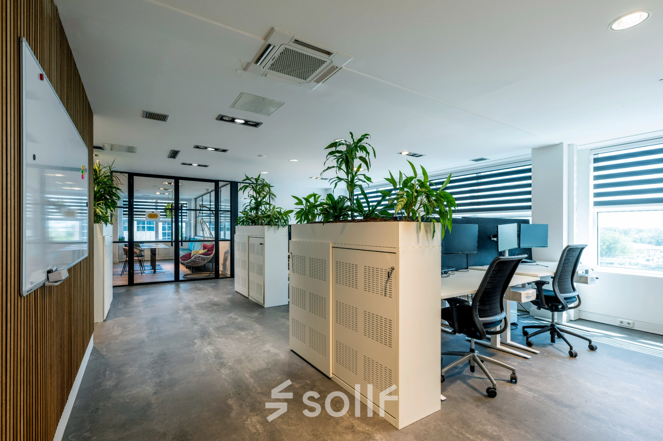 Modern office space at Overschiestraat 186 in Amsterdam De Schinkel featuring workstations with chairs and screens, divided by planters.