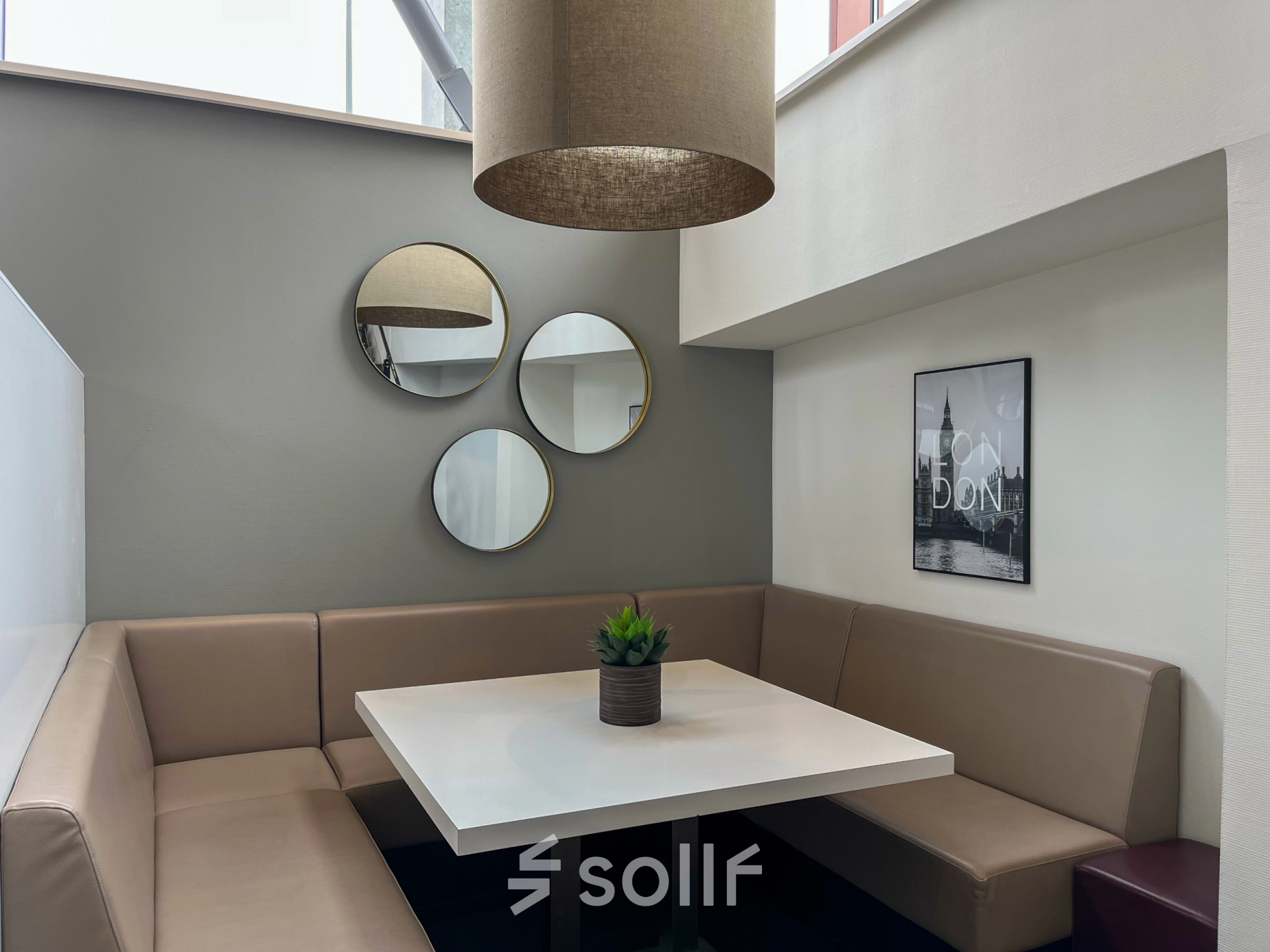 Cozy furnished office space available for rent in Amsterdam Duivendrecht, featuring a modern seating area with a table, cushions, and wall decor.