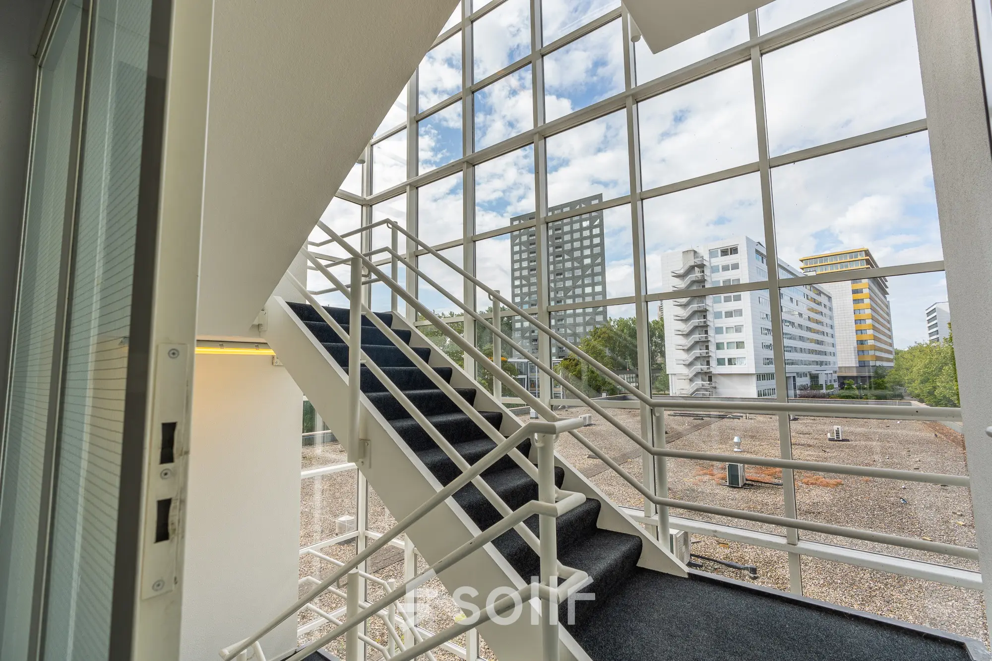 Staircase with large windows offering views of the surrounding Amsterdam East skyline at James Wattstraat 71.