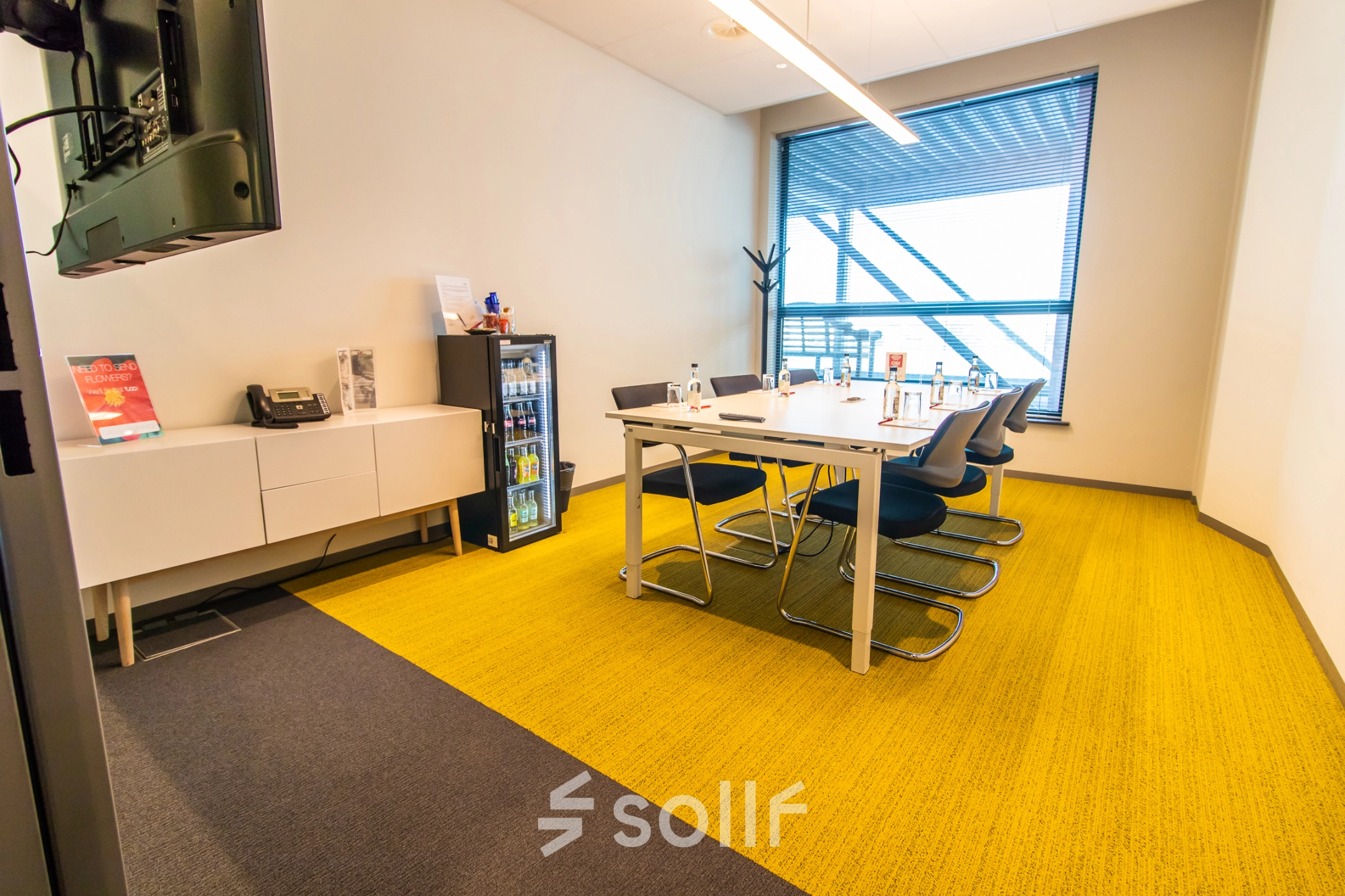 Office space rental at Piet Heinkade 55 in Amsterdam East featuring a modern conference room with a large table and chairs, bright yellow carpet, and a window view.