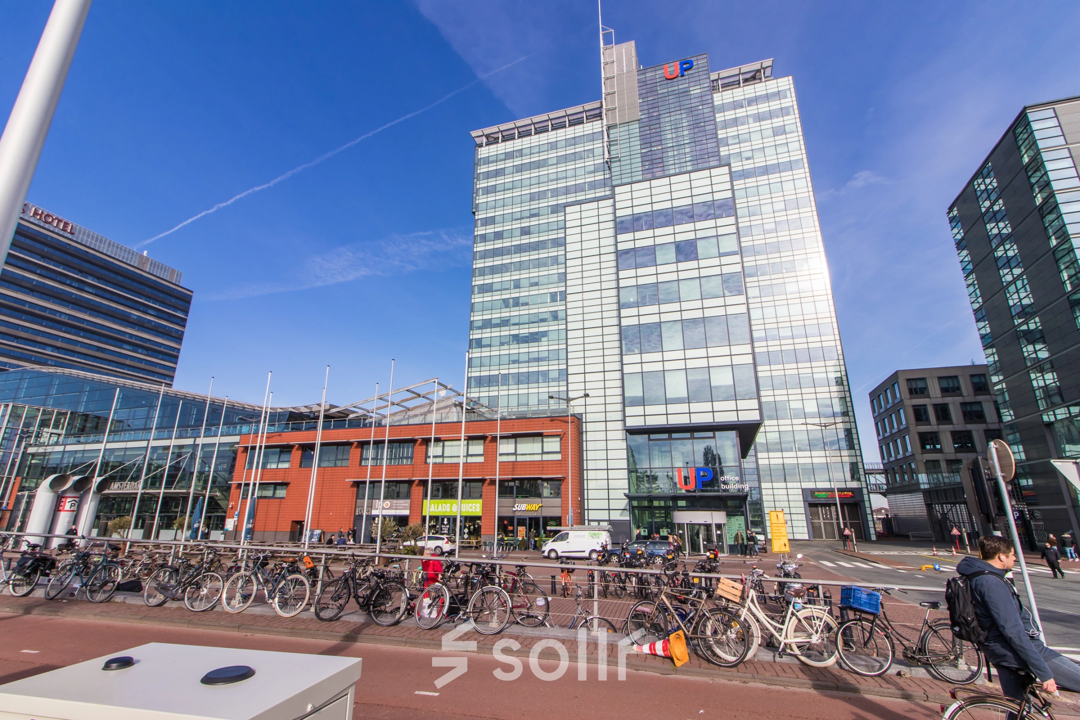 Exterior view of an office building at Piet Heinkade 55, Amsterdam East, featuring a modern glass facade. Ideal for those seeking office space rental in a prime location.