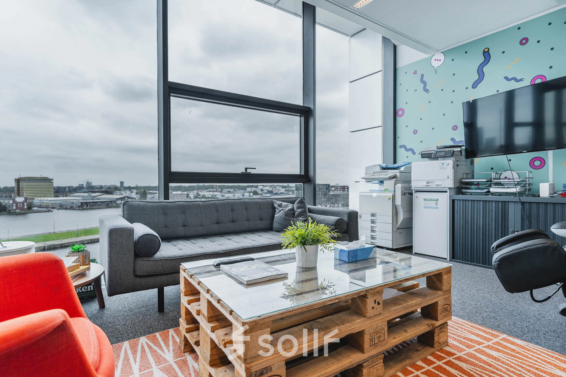 Bright office space at Piet Heinkade 95B in Amsterdam East with modern decor, featuring a comfortable seating area and a view of the city. Ideal for office space rental opportunities.