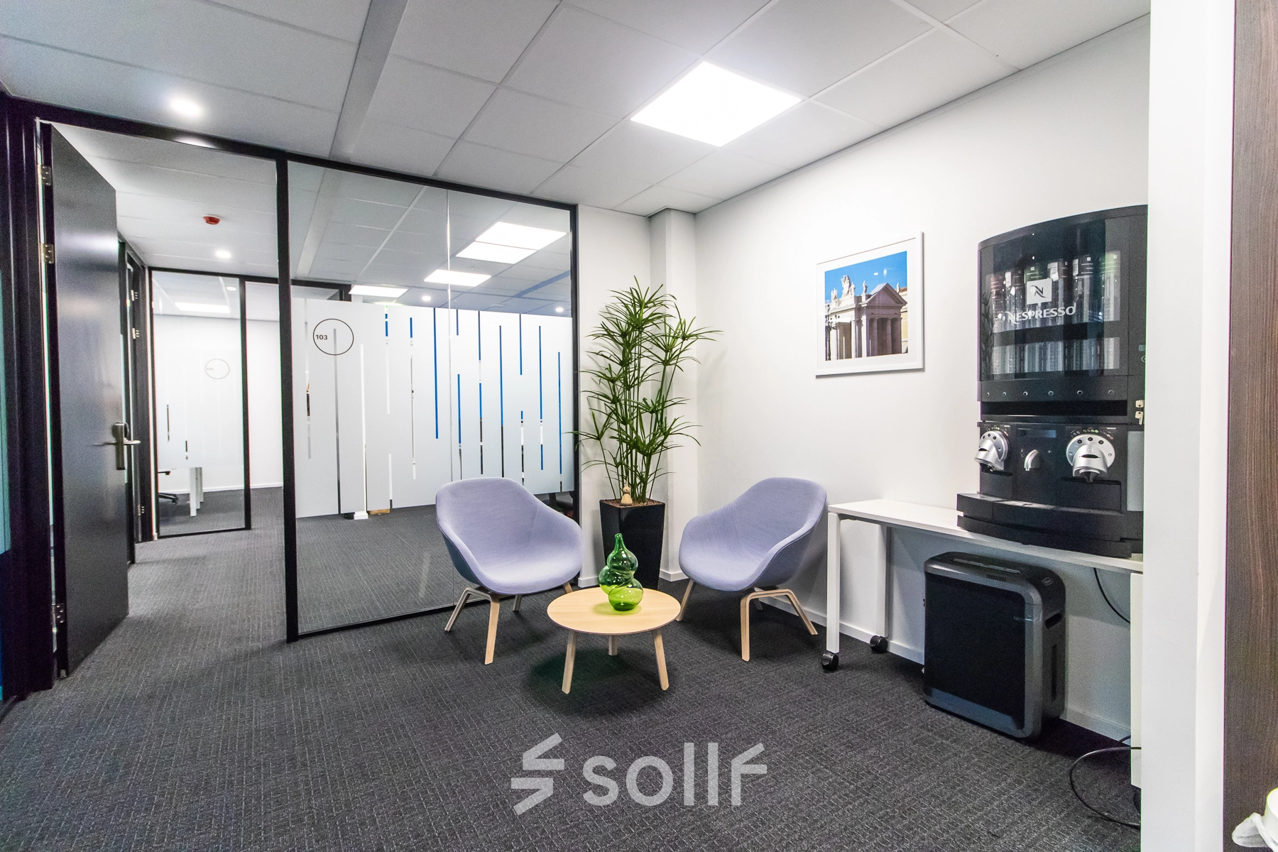 Modern office space in Amsterdam East with lounge chairs, a coffee machine, and a small table, perfect for short breaks. Ideal for those seeking office space rental.