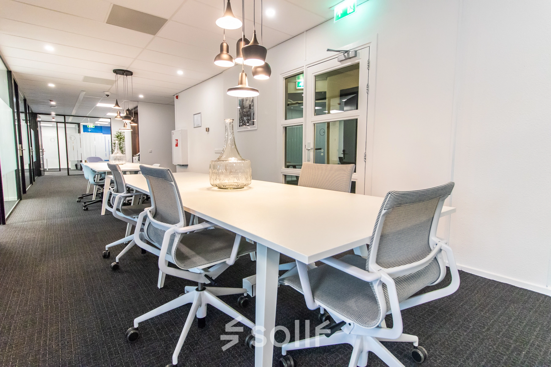Spacious, well-lit office with modern furnishings in Amsterdam East; ideal for office space rental. Features sleek tables and comfortable chairs for a professional working environment.
