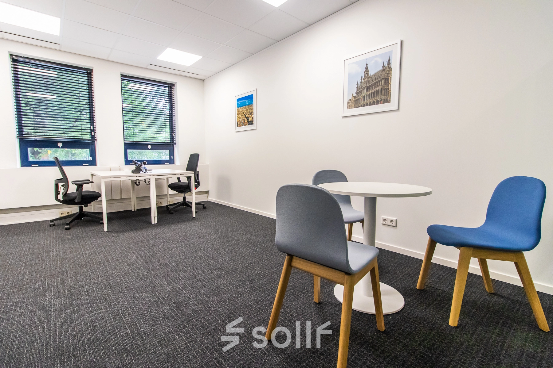 Bright office space rental at Rhijnspoorplein 10-38, Amsterdam East, with modern furnishings including desks and chairs, set against large windows for natural light.