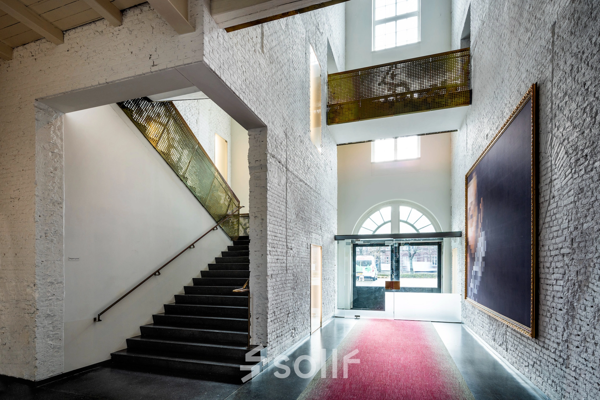 Entrance area at Sarphatistraat 370, Amsterdam East, featuring unique architecture and striking artwork - perfect for rent office space seekers.