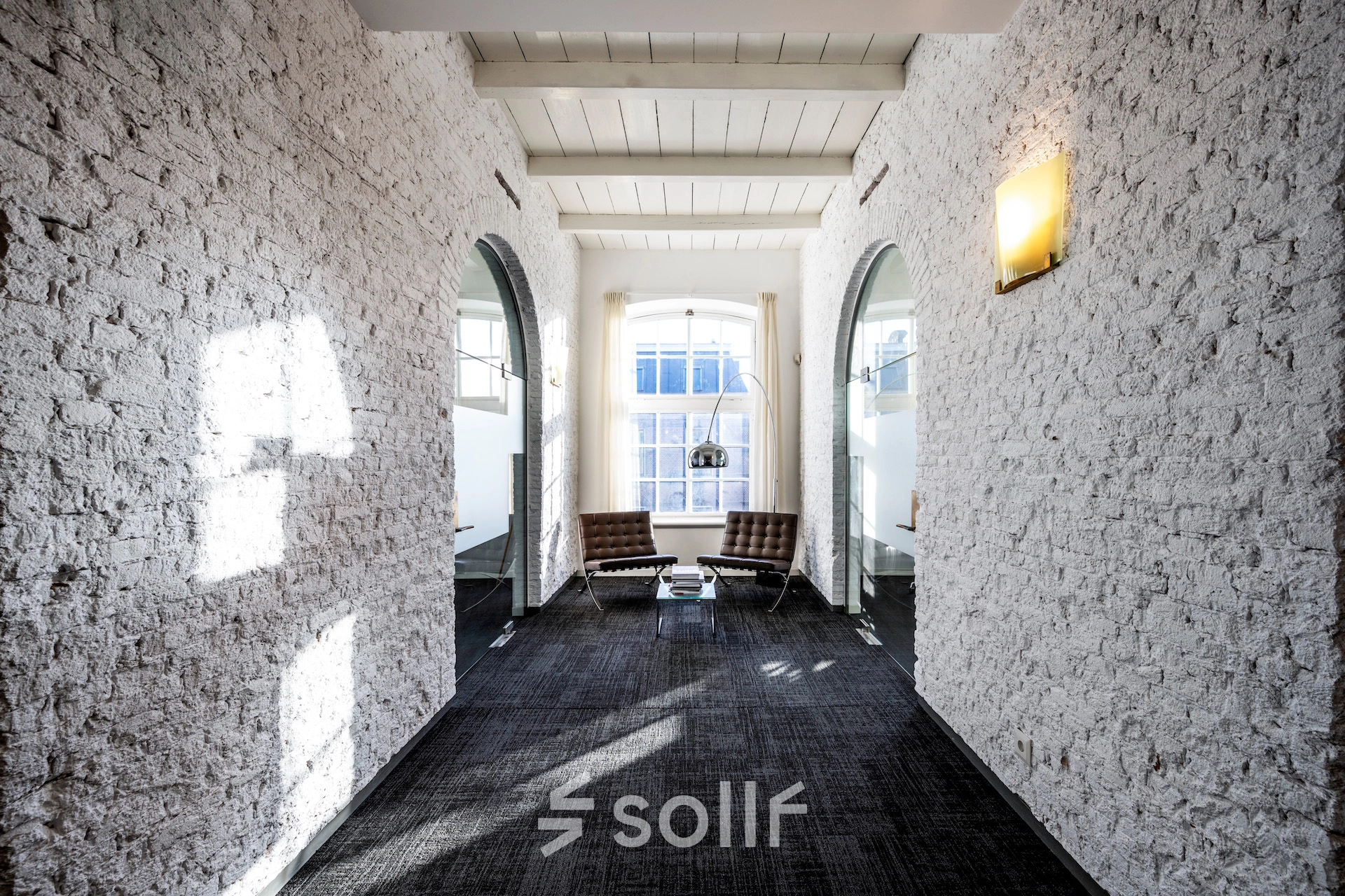 Bright office area at Sarphatistraat 370 in Amsterdam East with textured walls, seating, and natural light. Ideal office space rental location.