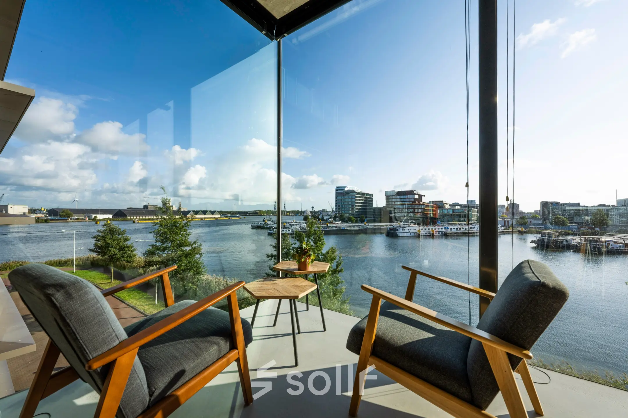 Bright office lounge area at Moermanskkade 109-113, Amsterdam, featuring two chairs and a view of the waterfront.