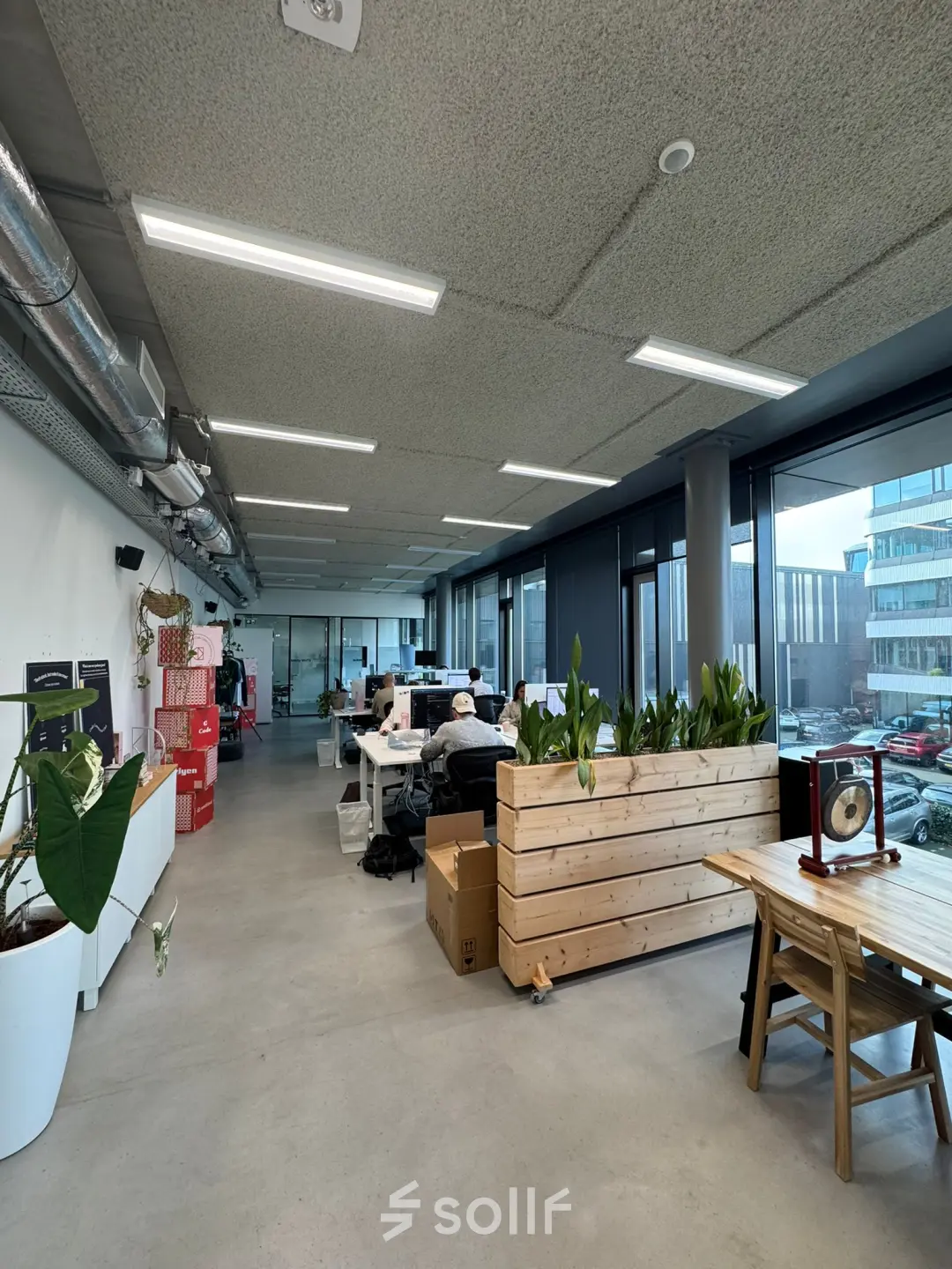 Spacious office space in Amsterdam Houthavens, featuring modern design with wooden planters and large windows for ample natural light. Ideal office to rent for vibrant workspaces.