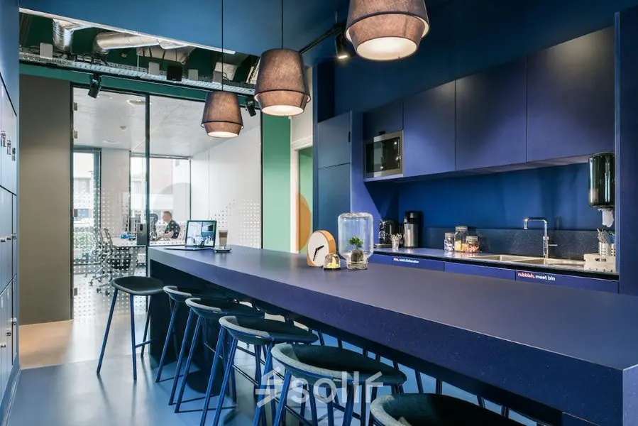 Modern office kitchen at Jan van Galenstraat 335, Amsterdam New-West, with vibrant blue design and bar seating, ideal for office space rental.
