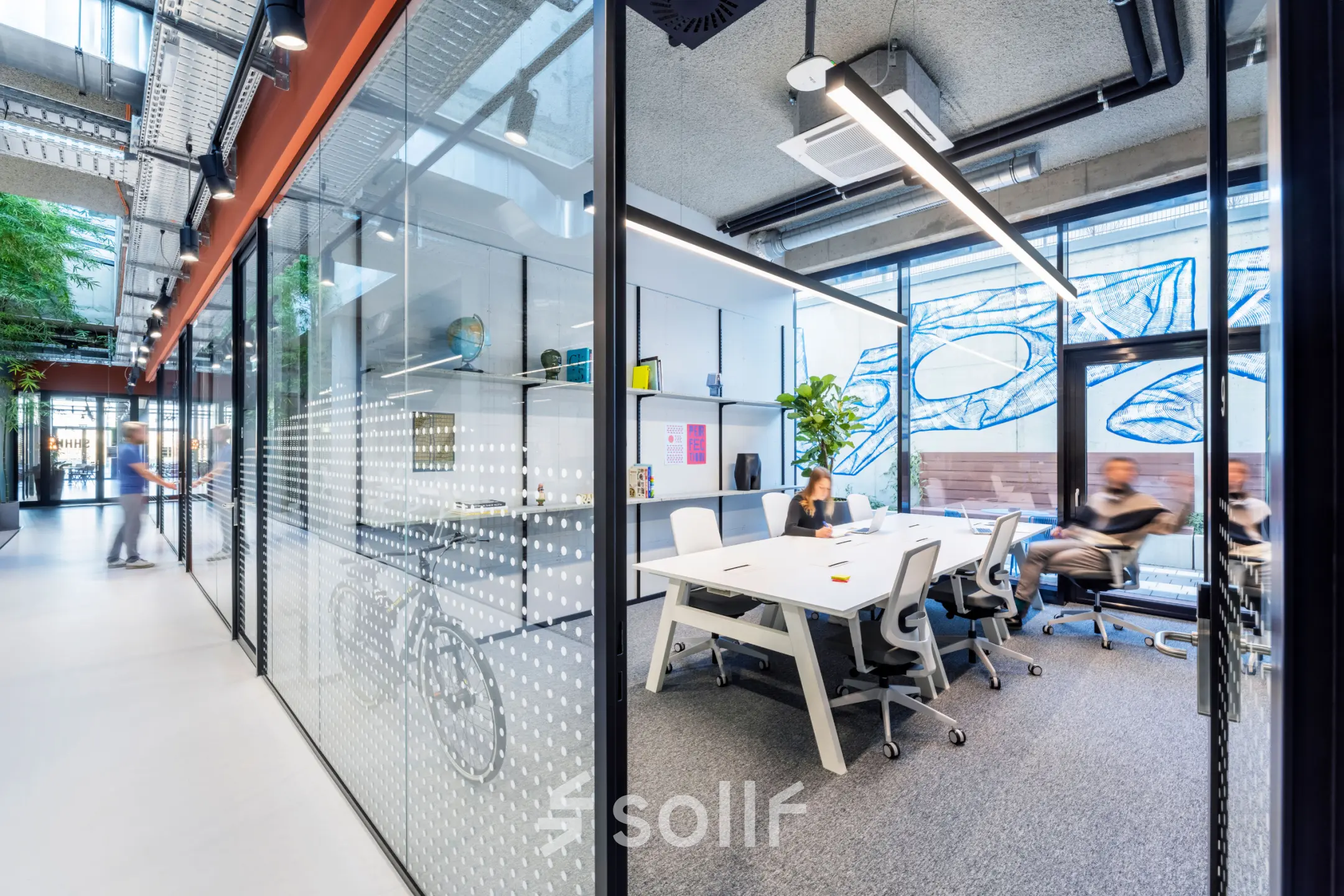 Modern office space for rent at Jan van Galenstraat 335, Amsterdam New-West, featuring a stylish conference room with people engaged in discussion around a large table.