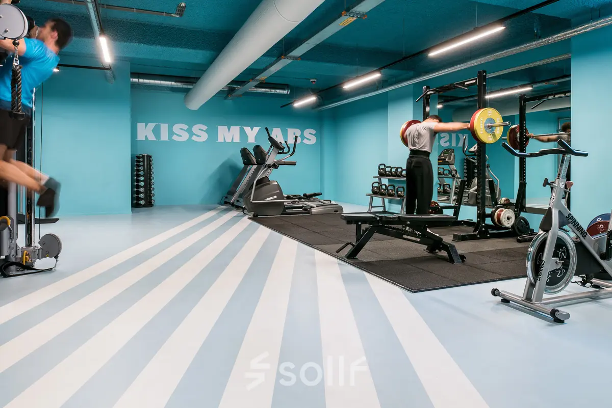 Gym area at Jan van Galenstraat 335, Amsterdam New-West, with equipment and people exercising.