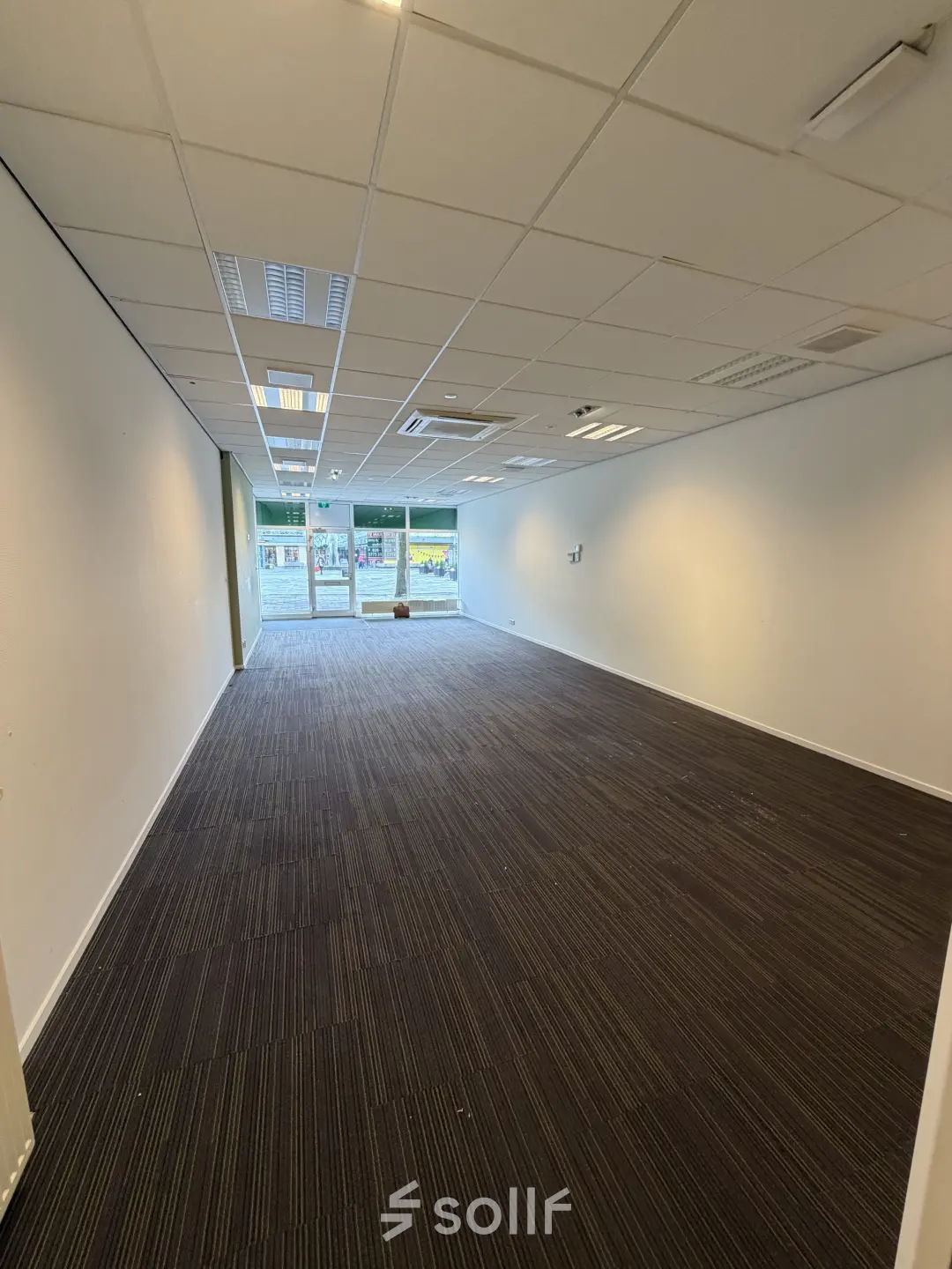 Spacious interior of an unfurnished office to rent at Buikslotermeerplein 430, Amsterdam North, with bright lighting and large windows at the far end.