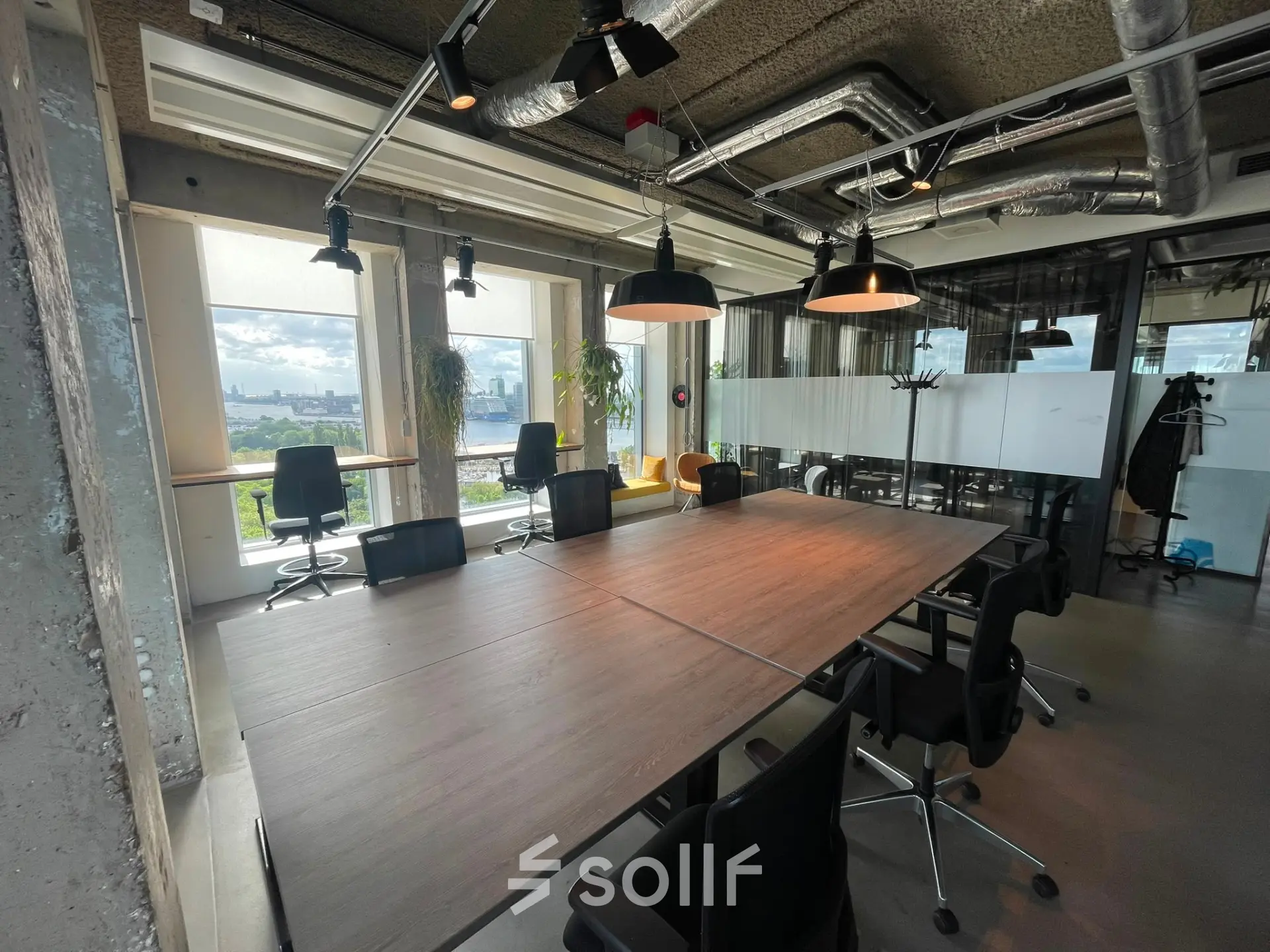 Modern furnished office space at Overhoeksplein 1, Amsterdam North, featuring a large conference table with chairs, perfect for those looking to rent office space with panoramic city views.