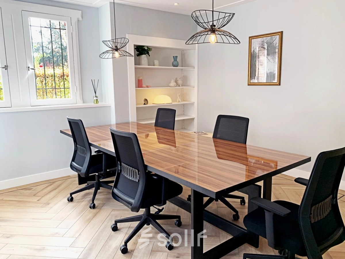 Bright office space rental in Amsterdam Old South with a wooden table and four chairs, under modern pendant lights. Ideal environment for meetings or collaborative work. Available for rent at Emmalaan 7-9.