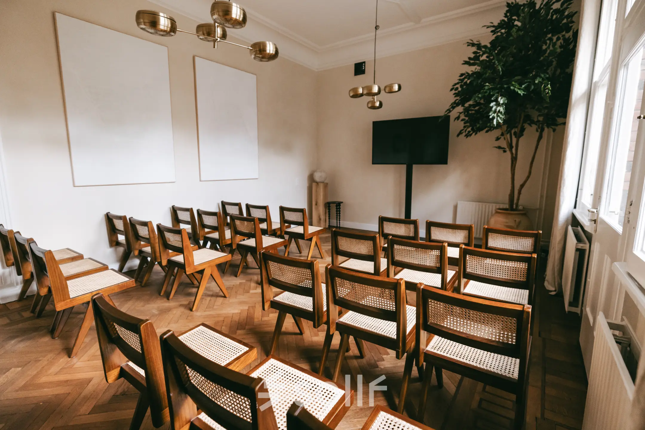 Light-filled conference room at Emmalaan 7-9 in Amsterdam Old South, featuring neatly arranged wooden chairs and a large screen. Ideal for office space rental.