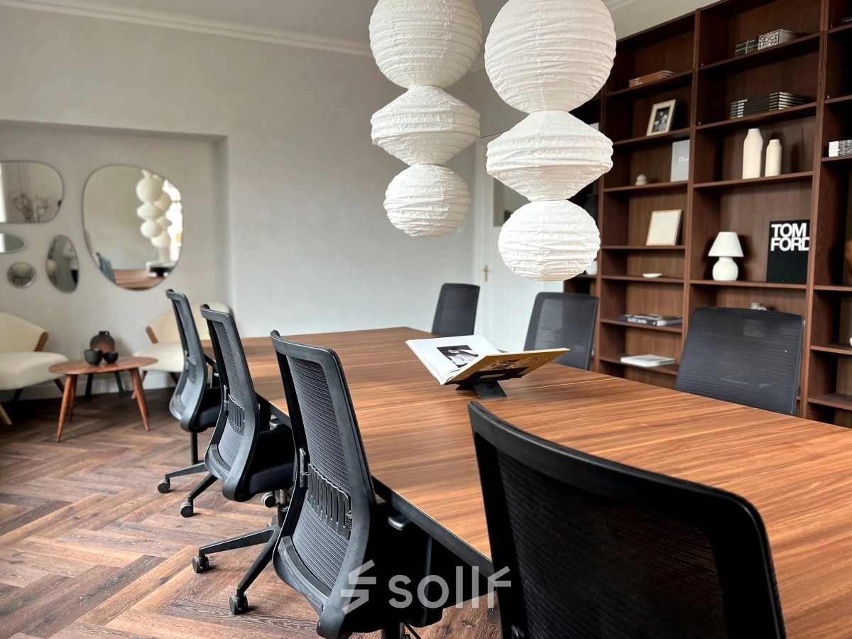 Office space with a long wooden table, black chairs, pendant lights, and a bookshelf, available for rent at Emmalaan 7-9, Amsterdam Old South.
