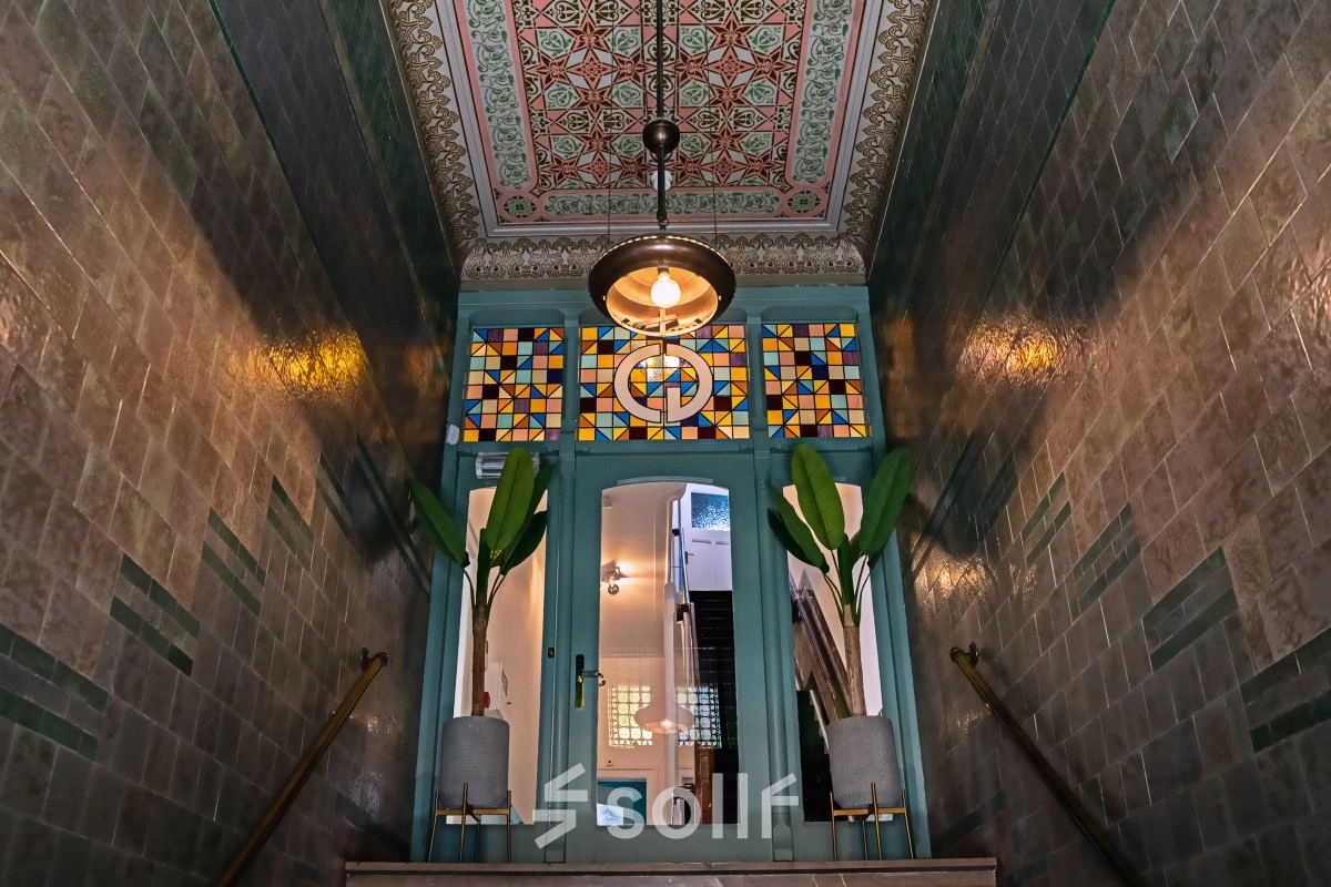 Entrance area at Emmalaan 7-9, Amsterdam Old South, showcasing decorative tiles and stained glass, perfect for those looking to rent office space.