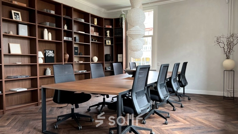 Furnished office space at Emmalaan 7-9, Amsterdam Old South, featuring a meeting table with chairs and wooden shelving in the background, ideal for office space rental.