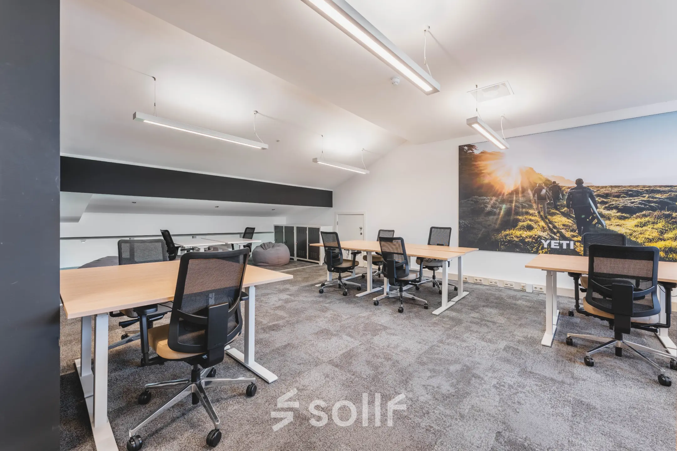 Modern office space with multiple desks and chairs, located in Olympisch Stadion, Amsterdam Old South, available for rent. Large wall art and ample lighting enhance the professional environment.