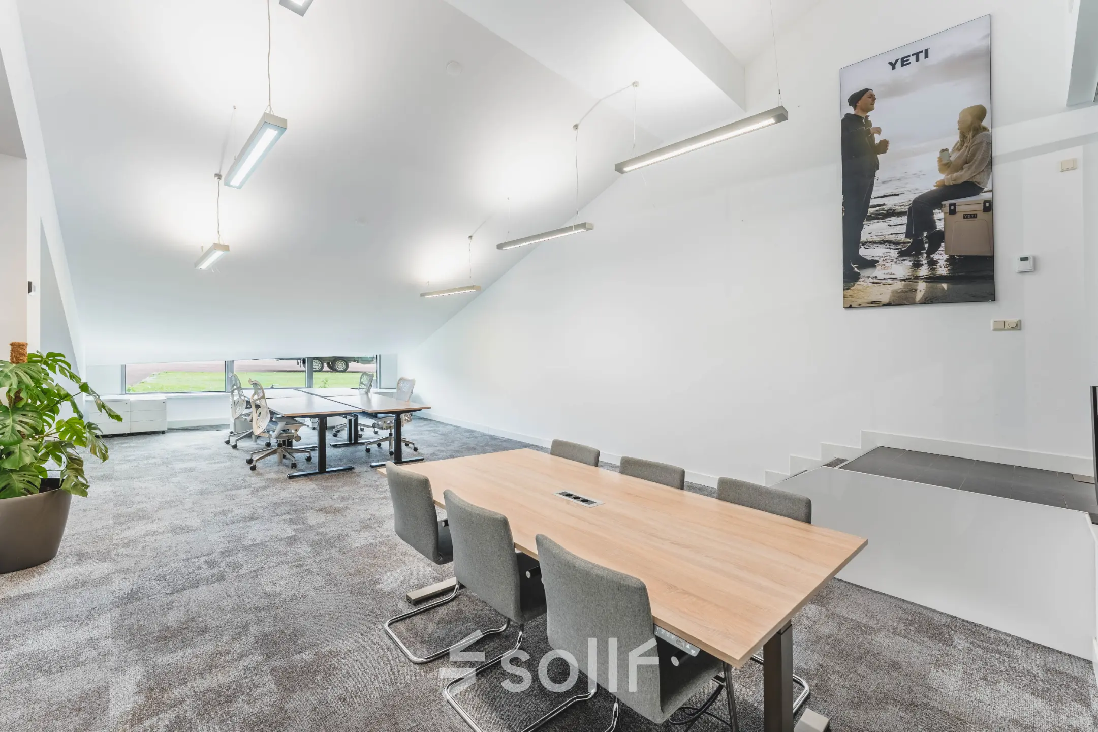 Modern office space at Olympisch Stadion 24-28 features a well-lit, open workspace with a conference table and a seating area near a window. Ideal for those seeking office space rental in Amsterdam Old South.