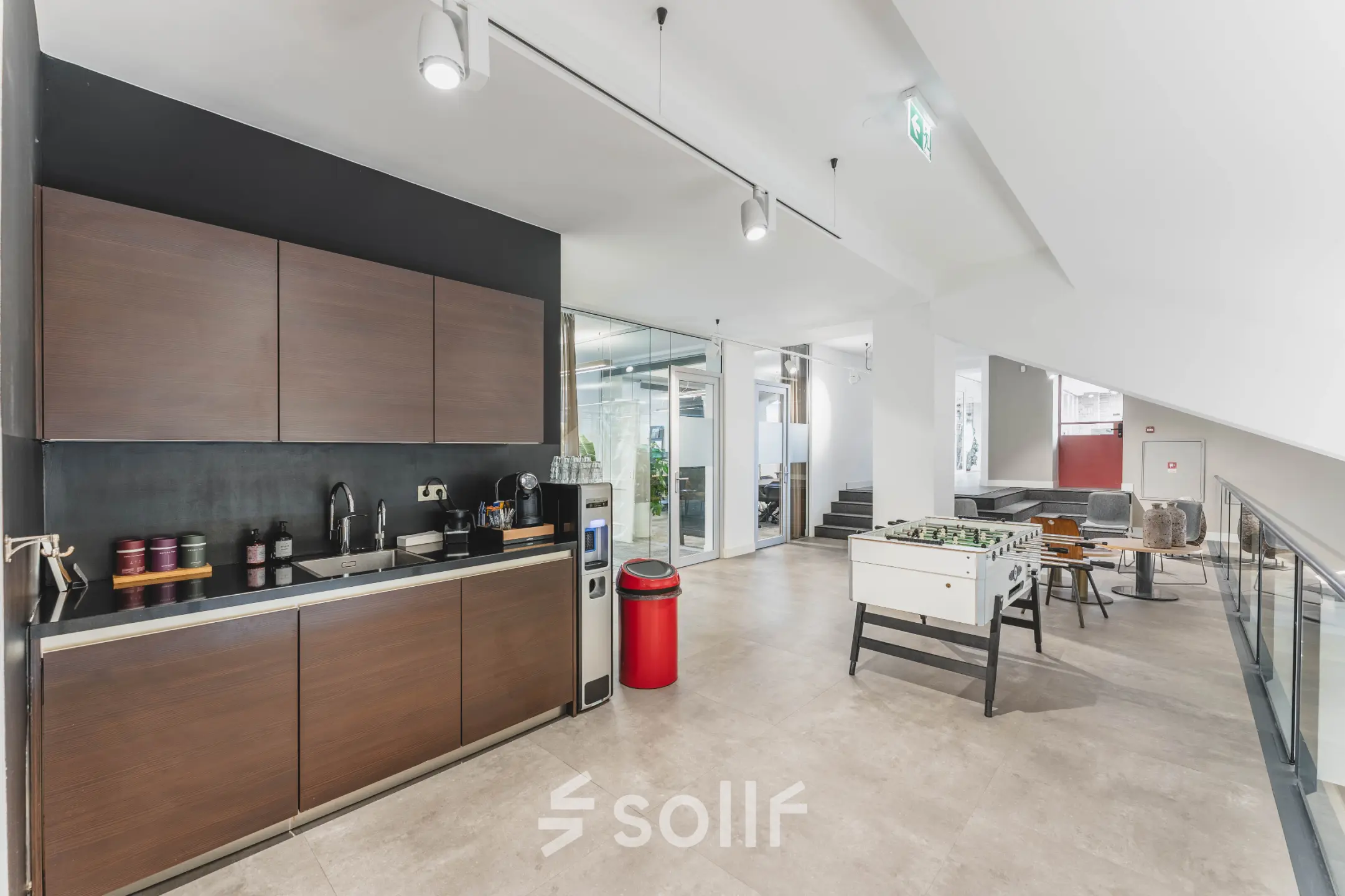 Modern office space rental in Amsterdam Old South featuring a sleek kitchenette and spacious recreational area with a foosball table at Olympisch Stadion 24-28.
