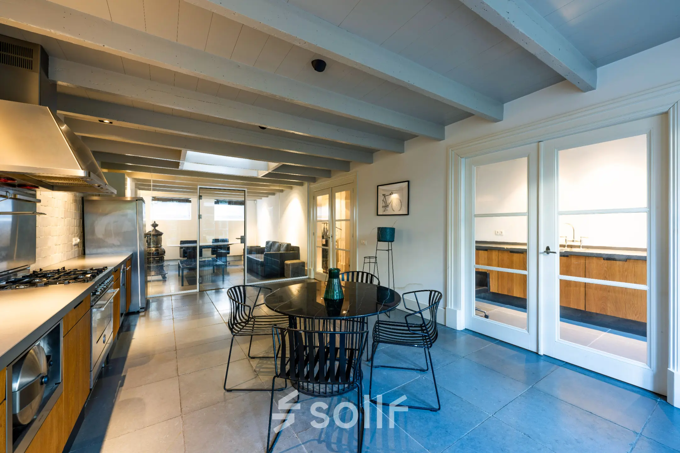 Modern office space with sleek furnishings in Amsterdam Old South, featuring a round table, stylish chairs, and an elegant kitchen area, ideal for office space rental.