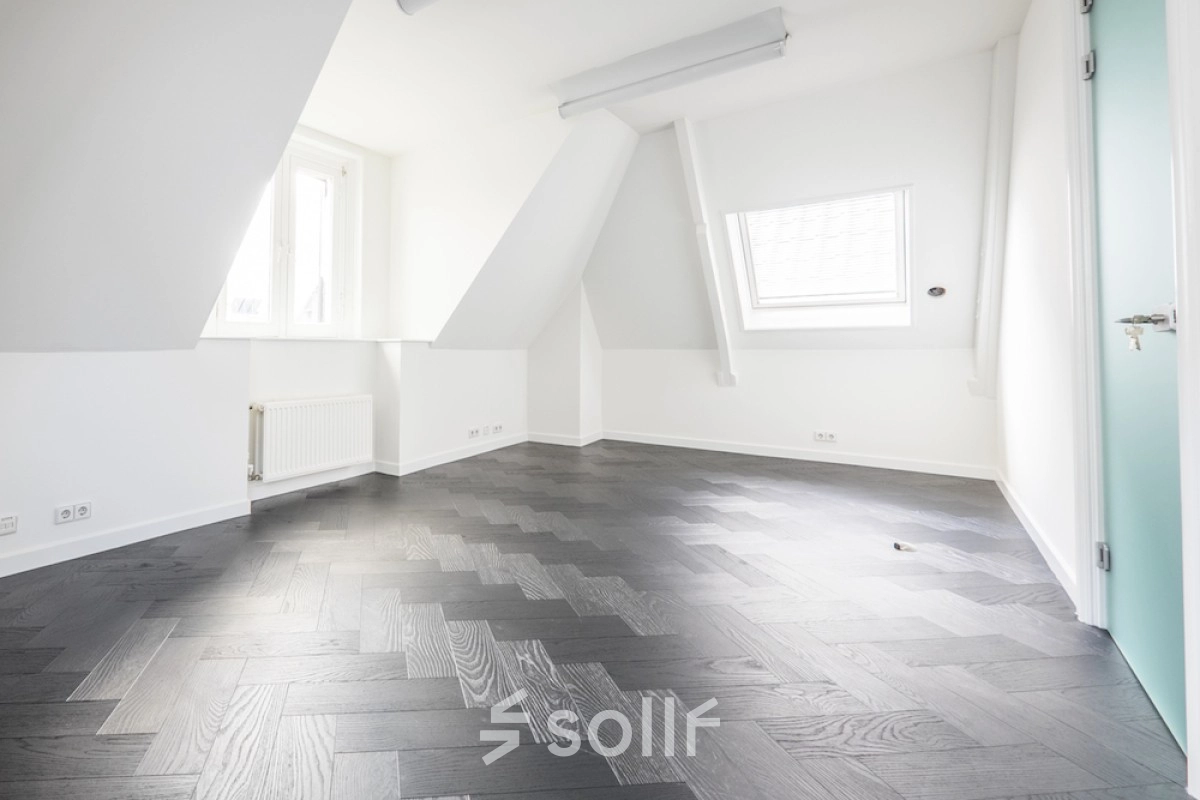 Bright, empty interior office space with sloped ceilings and wooden flooring at Sophialaan 21, ideal for office space rental in Amsterdam Old South.