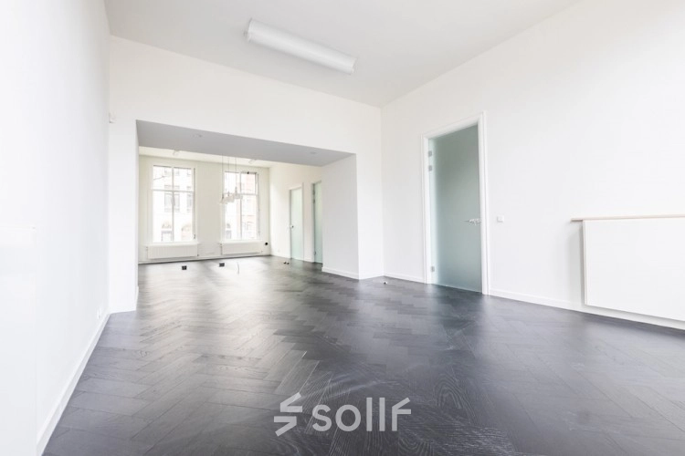 Spacious, unfurnished office space with dark wooden floors and large windows at Sophialaan 21, Amsterdam Old South. Ideal for office space rental.