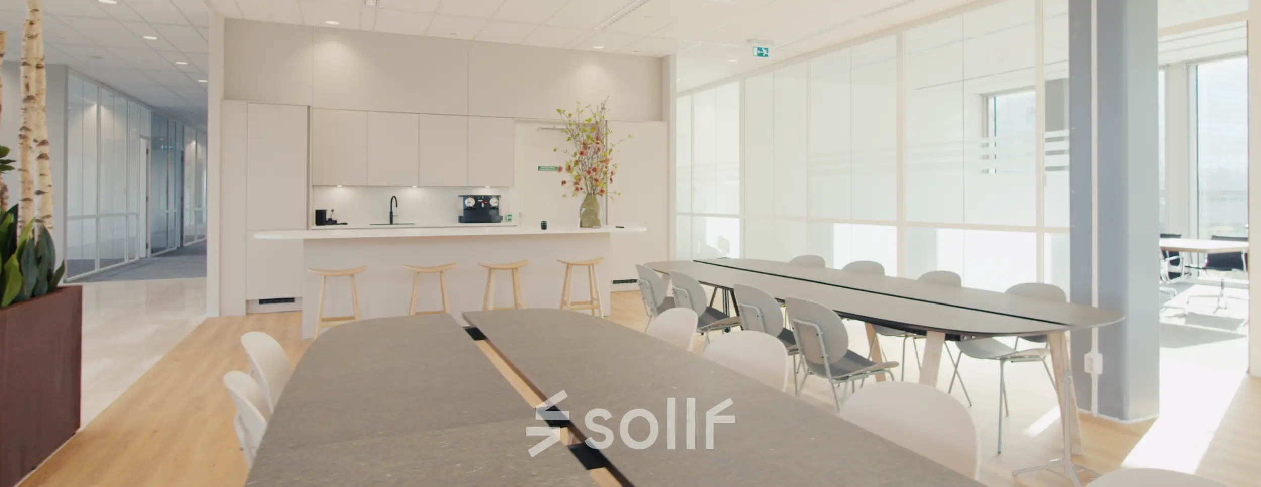 Modern office space with long tables and bar stools, ideal for meetings or casual gatherings.